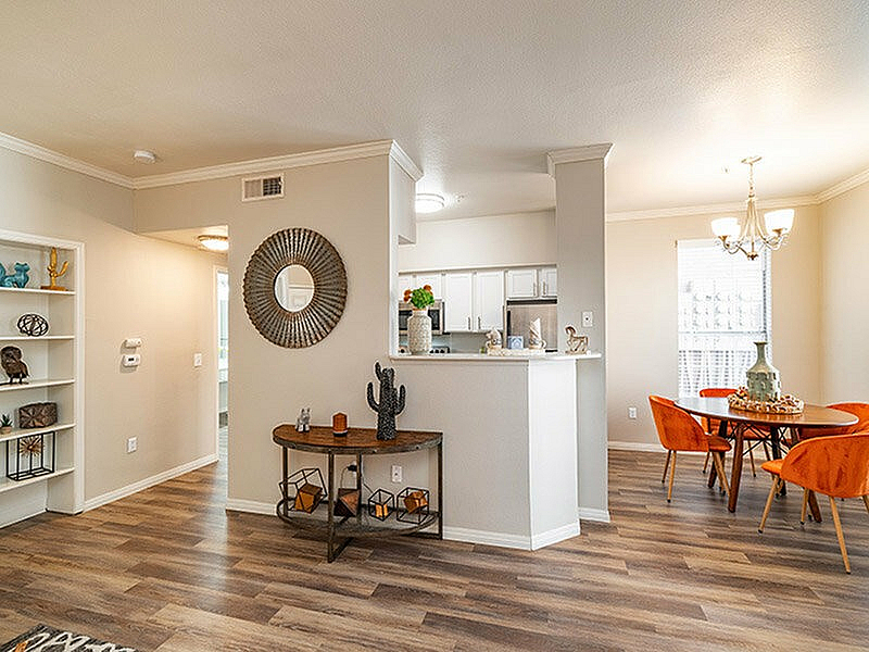 Charming open-concept living space featuring elegant wood flooring, a stylish dining area, and a modern kitchen with sleek countertops.