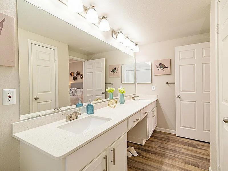 Bright and elegant bathroom featuring a double vanity with sleek white countertops, contemporary lighting, and stylish decor.