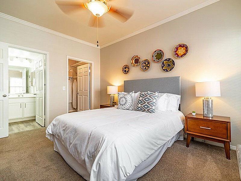 Inviting bedroom with plush carpet, elegant decor, and ample natural light, featuring a queen bed, stylish nightstands, and an ensuite bathroom.