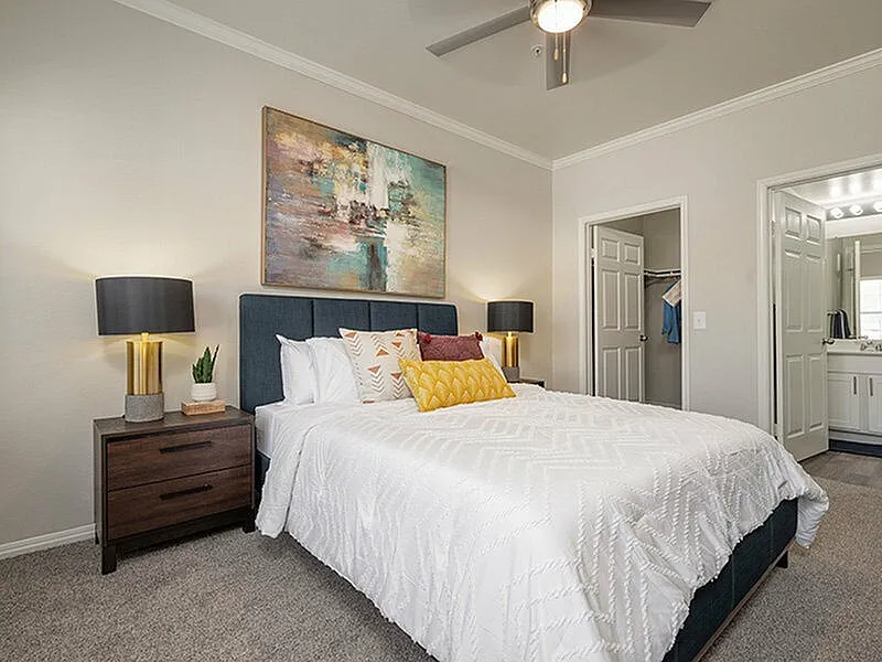 Inviting bedroom with elegant decor, stylish art, and cozy bedding, adjacent to a modern en-suite bathroom.