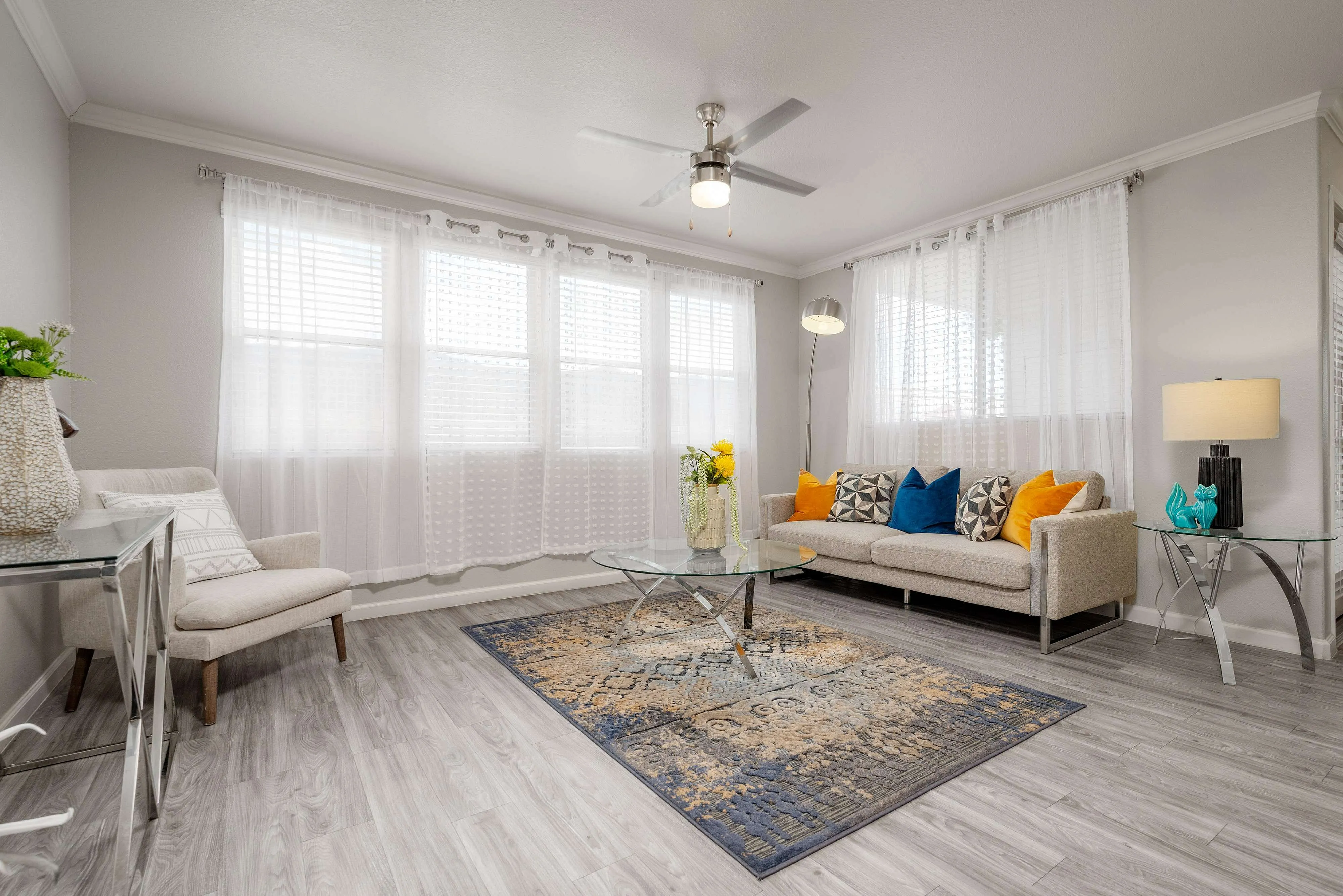 Bright and welcoming living room with large windows, modern furniture, vibrant cushions, and elegant decor.