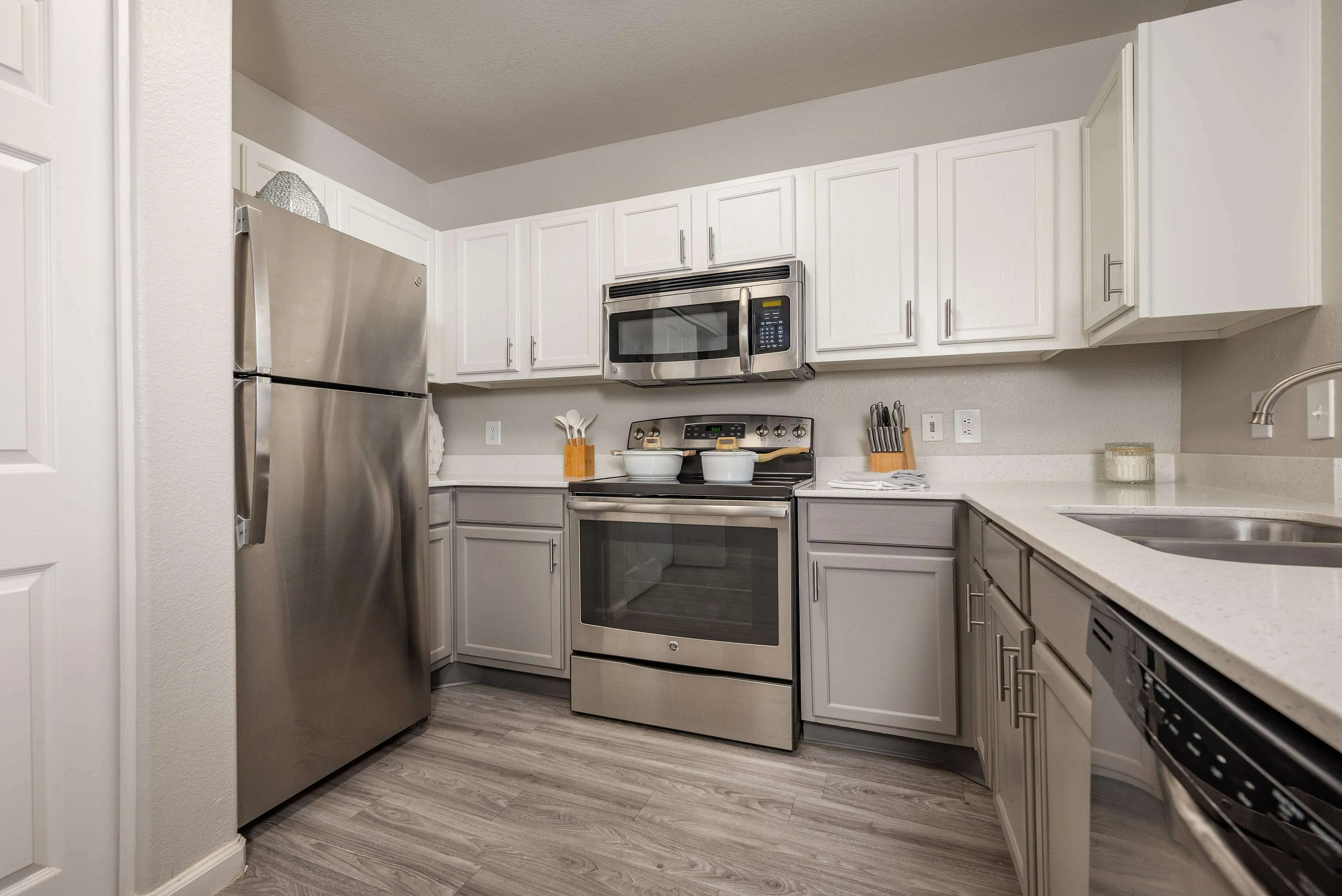 Modern kitchen with sleek stainless steel appliances and elegant white cabinetry, featuring ample counter space and stylish wood flooring.