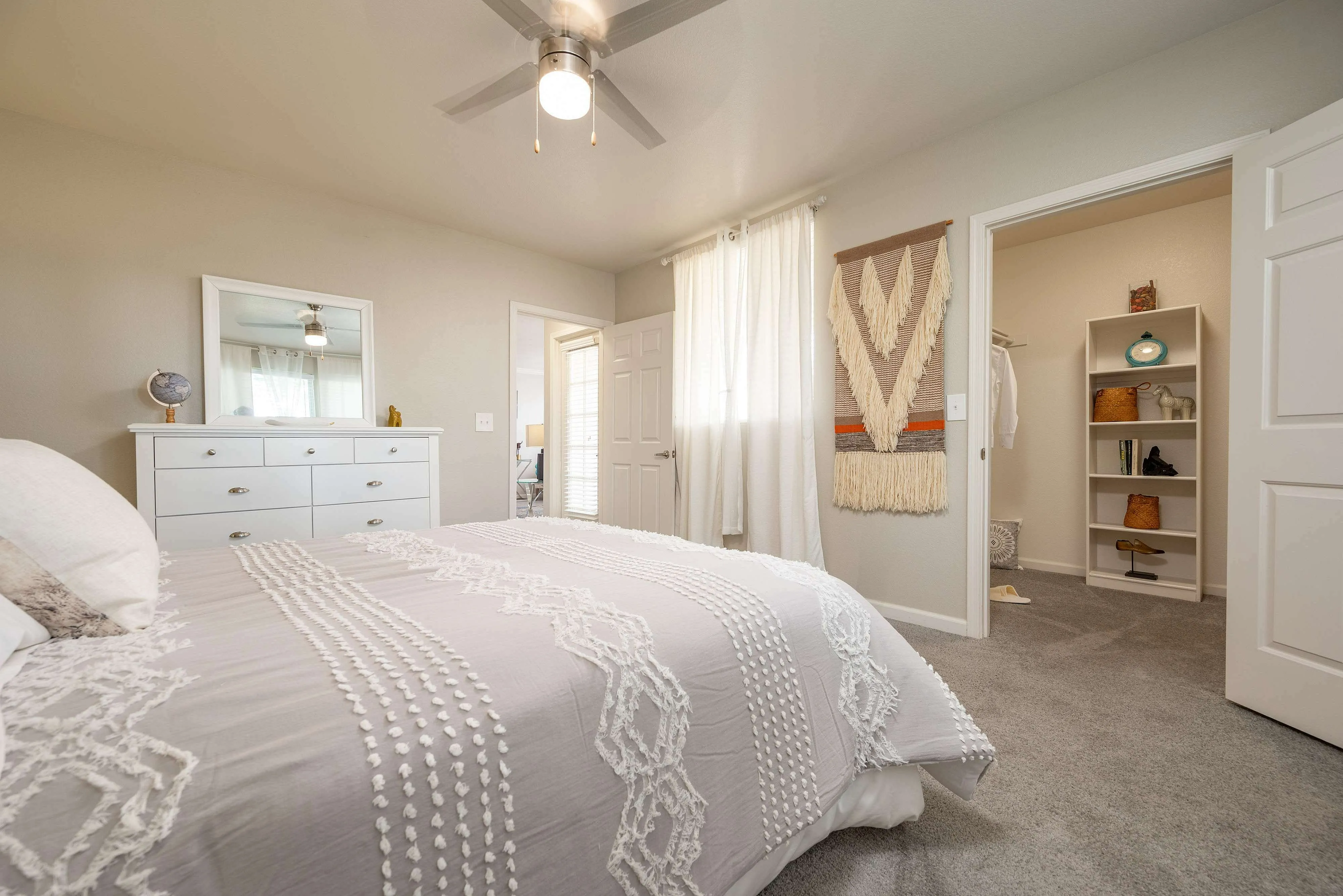 Cozy bedroom with elegant decor, featuring a stylish dresser, soft bedding, and a spacious walk-in closet.