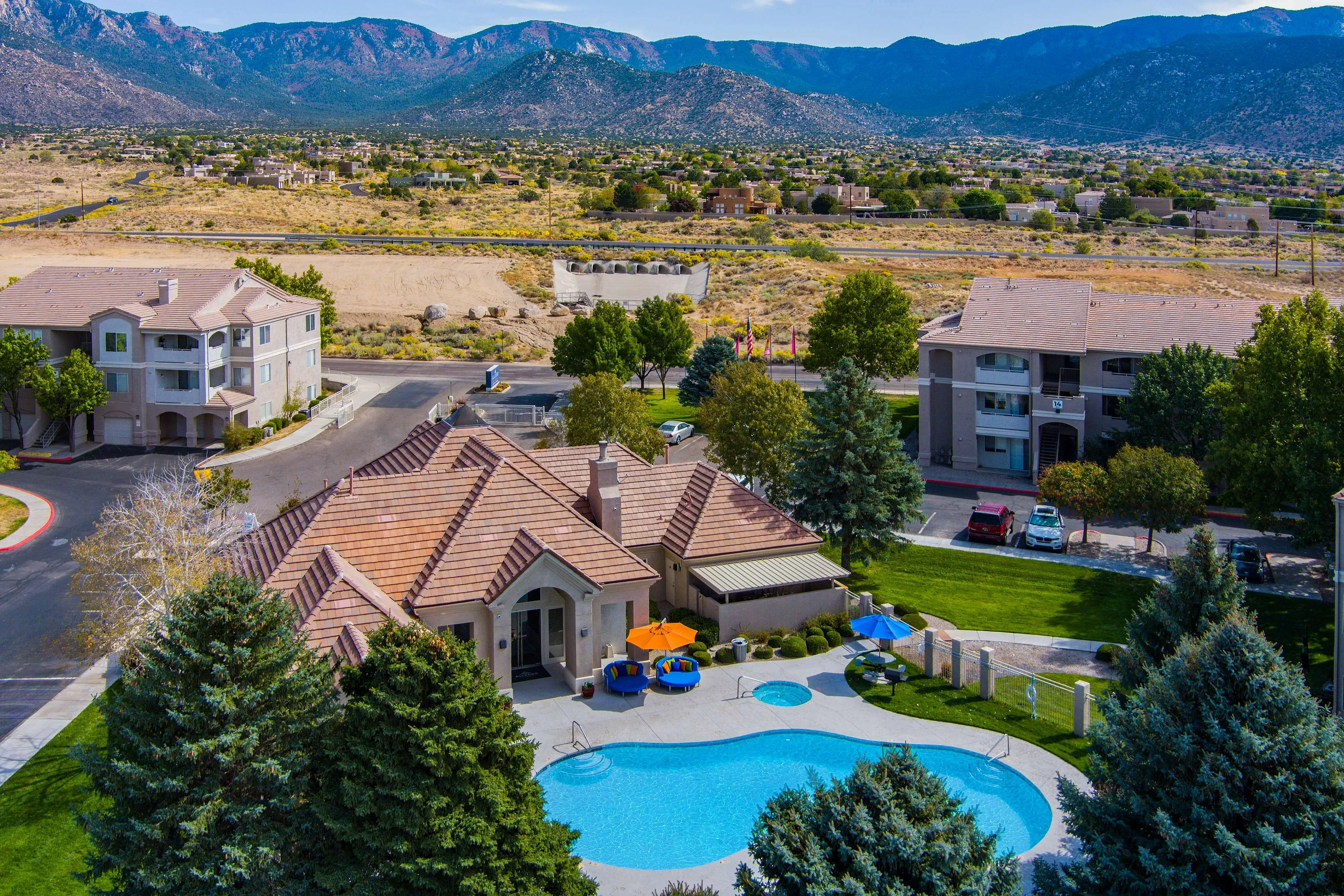 Gorgeous apartment complex with a sparkling blue pool, surrounded by lush greenery and mountain views, offering a tranquil and luxurious living experience.