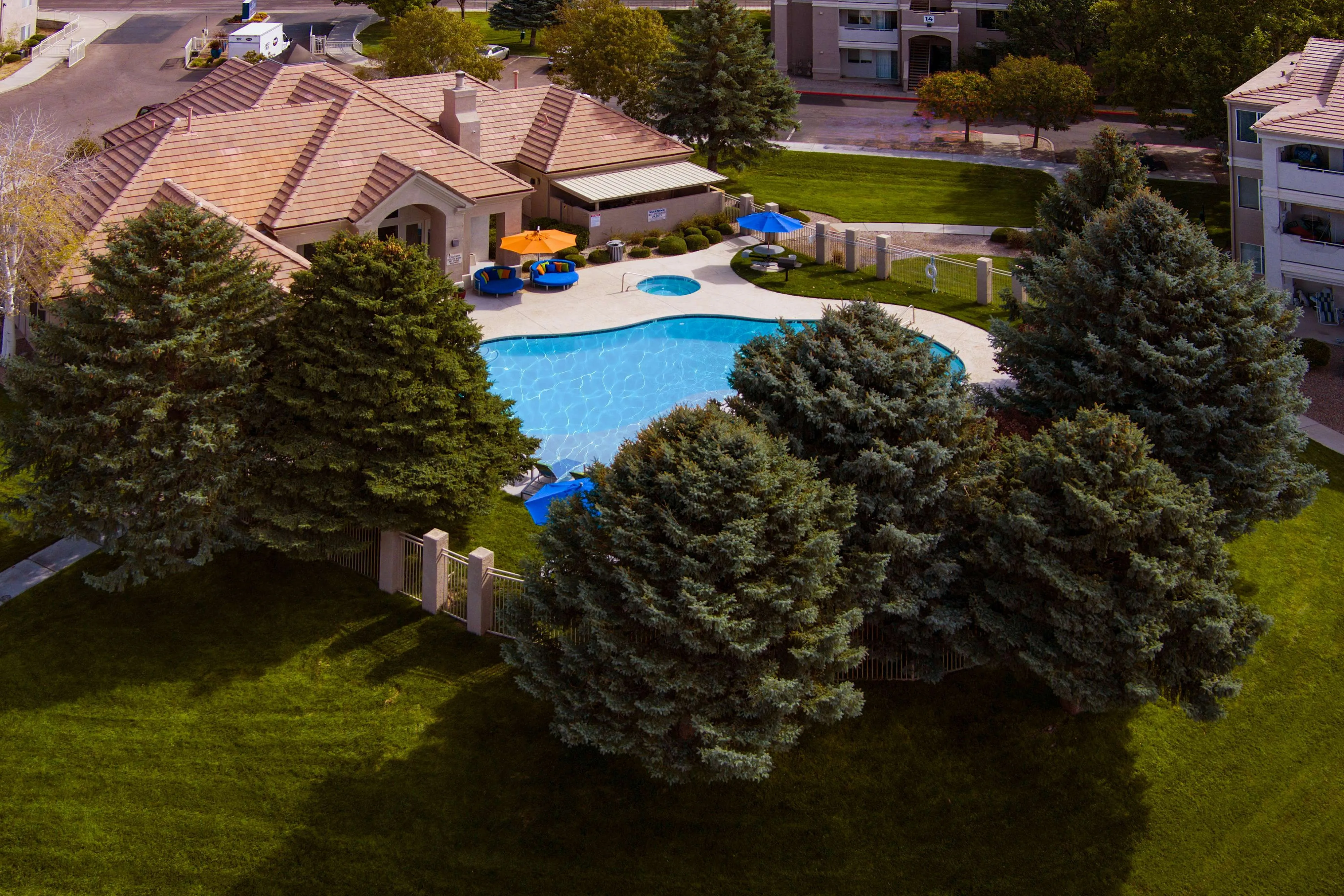 Charming residential complex with a sparkling blue pool, surrounded by lush greenery and spacious outdoor seating area.