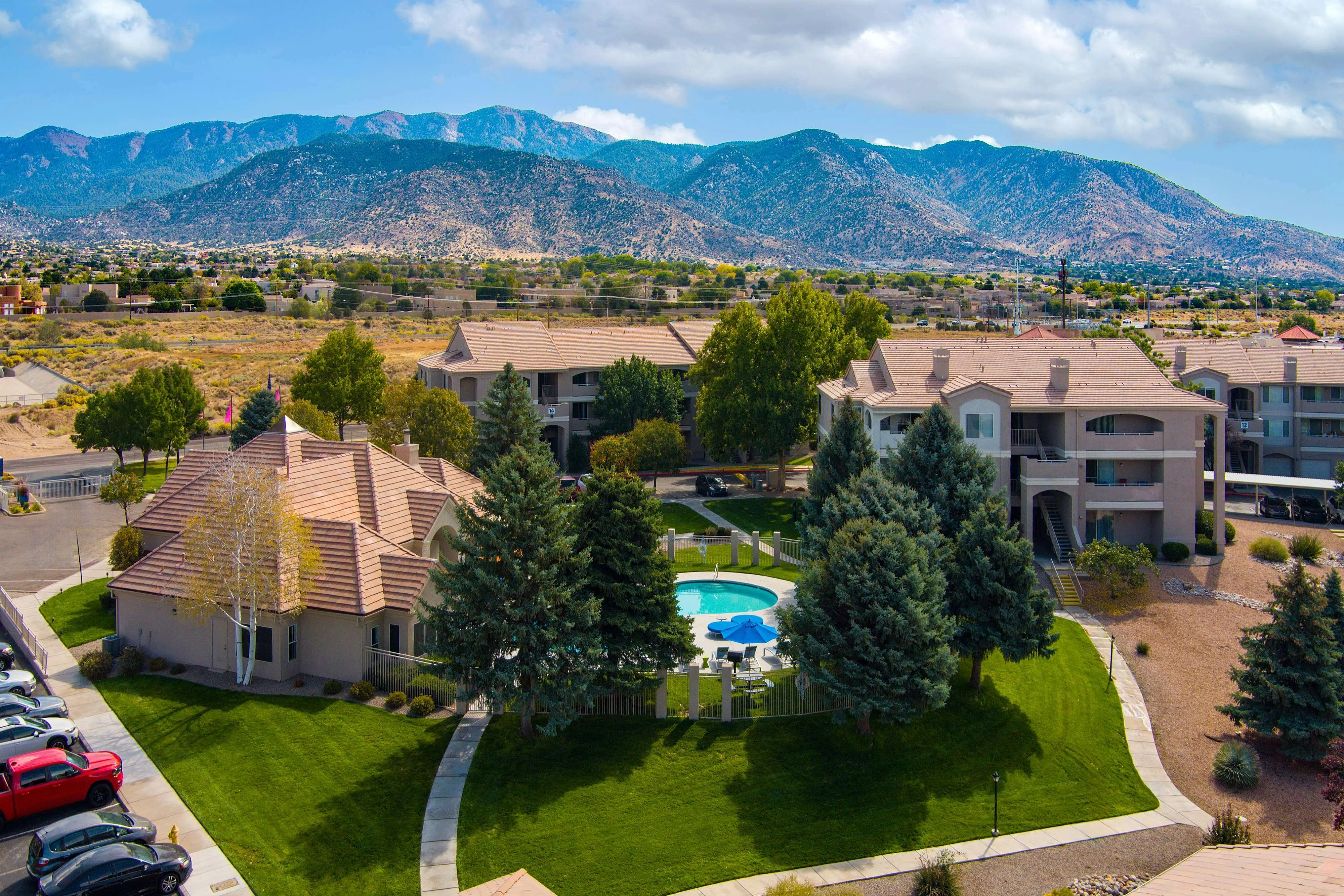 Charming residential complex with scenic mountain views, lush greenery, and a sparkling central pool, offering a tranquil living environment.