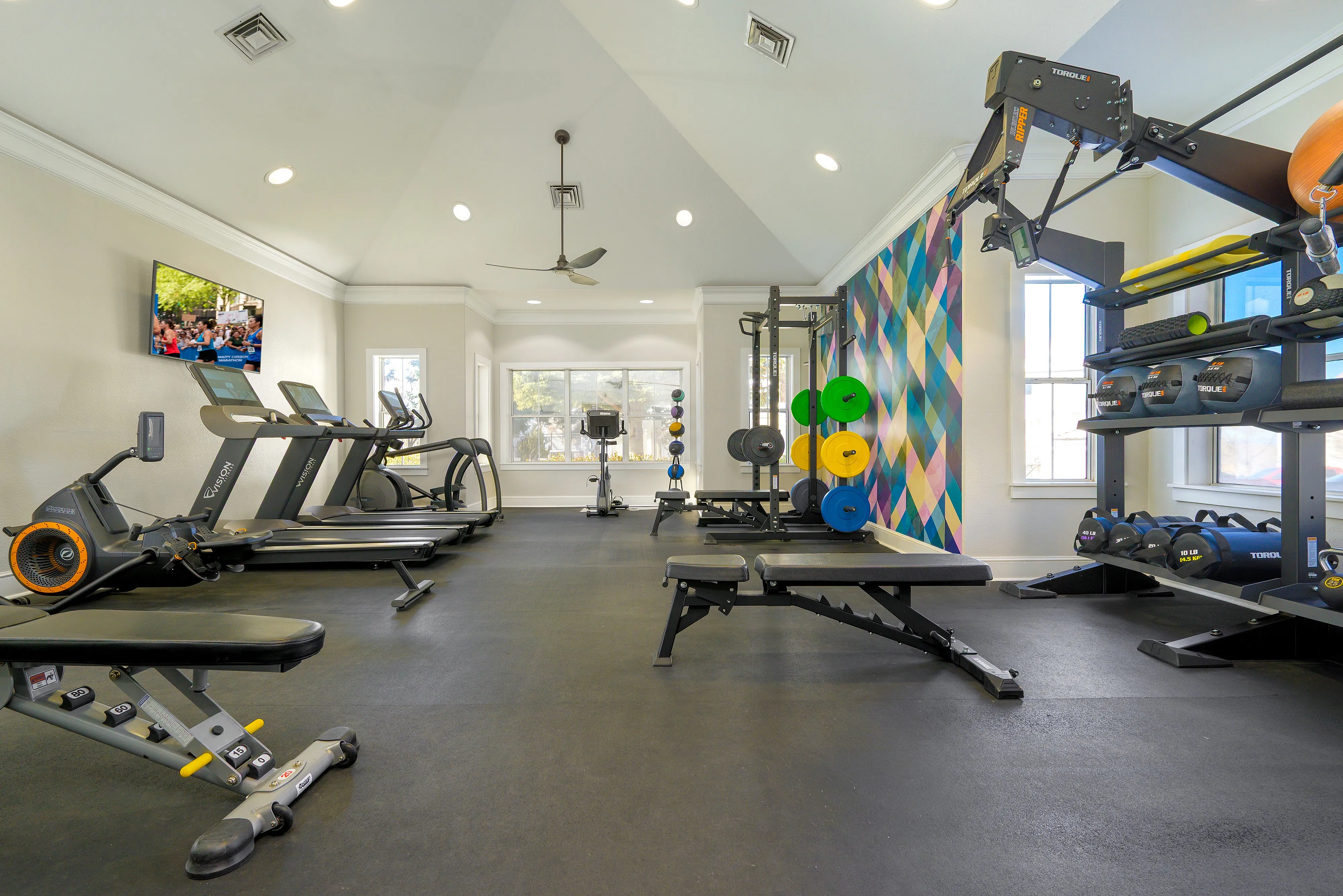 Modern fitness center with state-of-the-art equipment, colorful decor, and ample natural light.