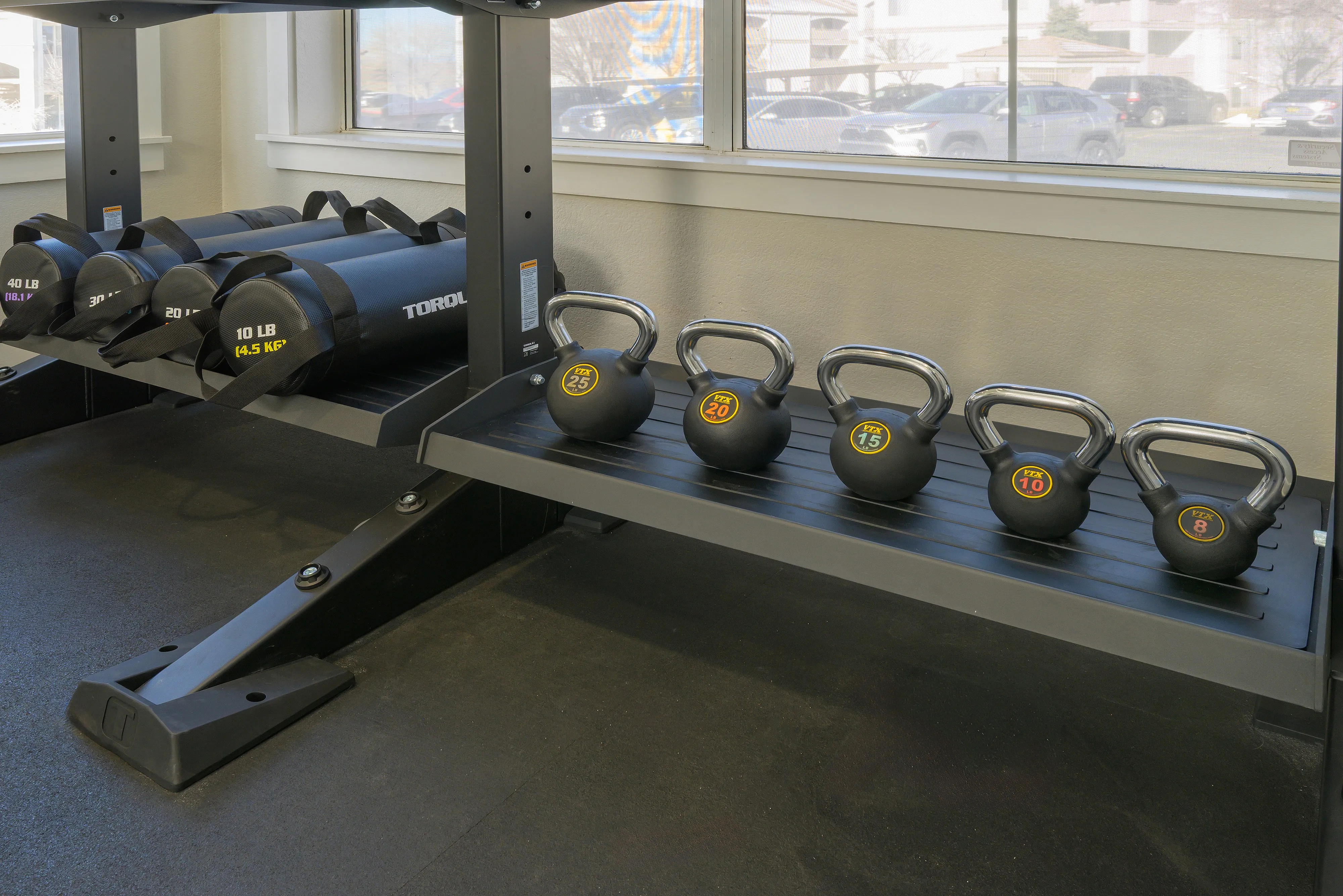 Modern fitness room showcasing a sleek set of kettlebells and weighted foam rollers, perfect for diverse workout routines.