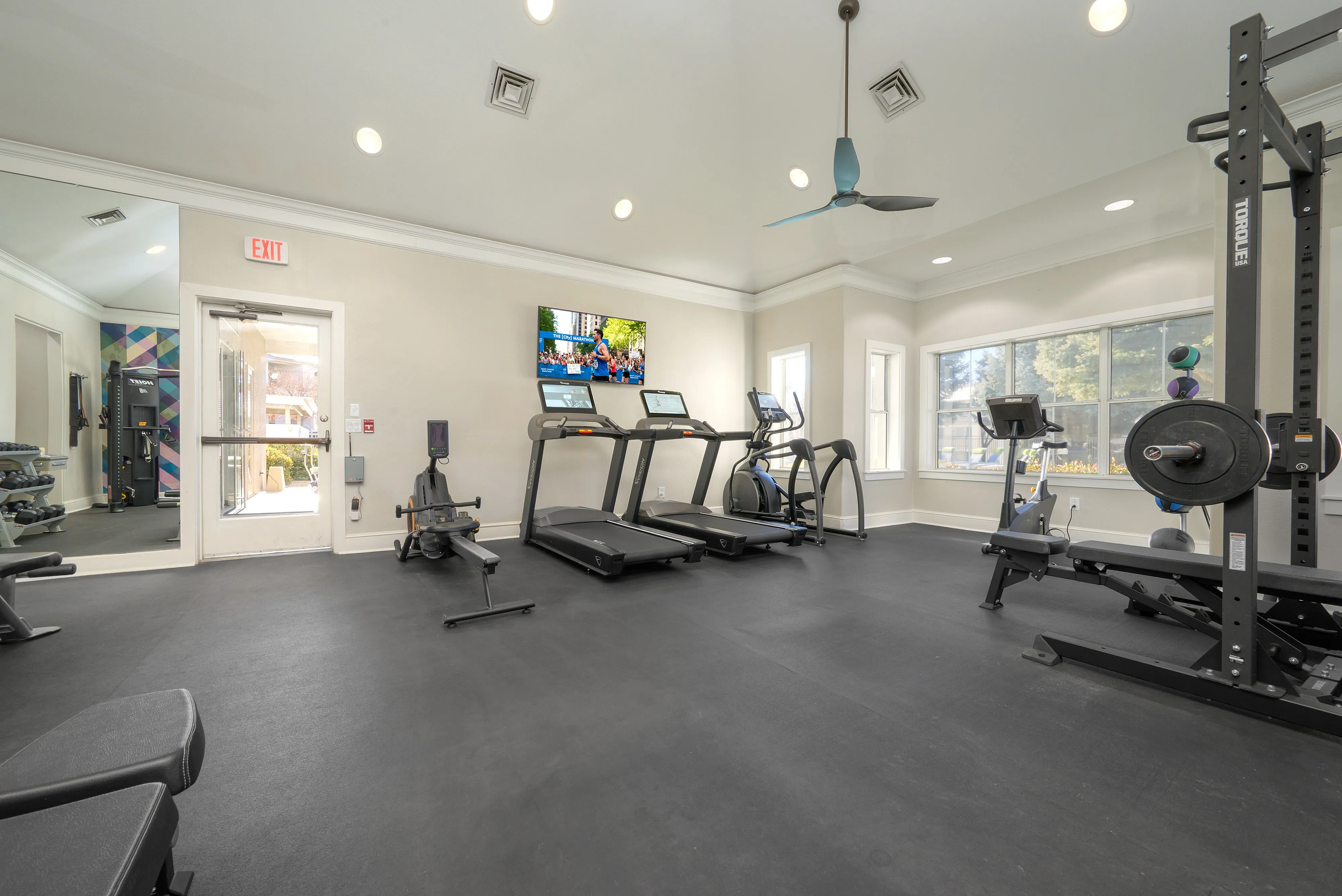 Bright and modern gym featuring state-of-the-art equipment, including treadmills, a rowing machine, and a weightlifting area.