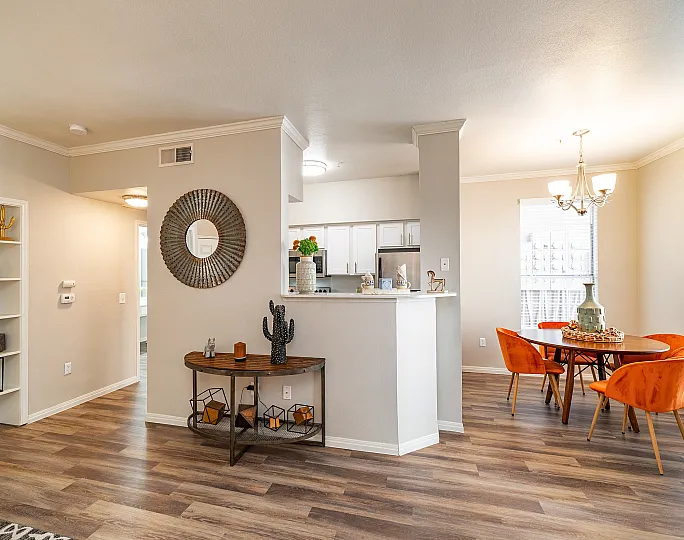 Bright and inviting open-concept living space featuring a stylish dining area with orange chairs, modern kitchen with sleek finishes, and chic decor elements.