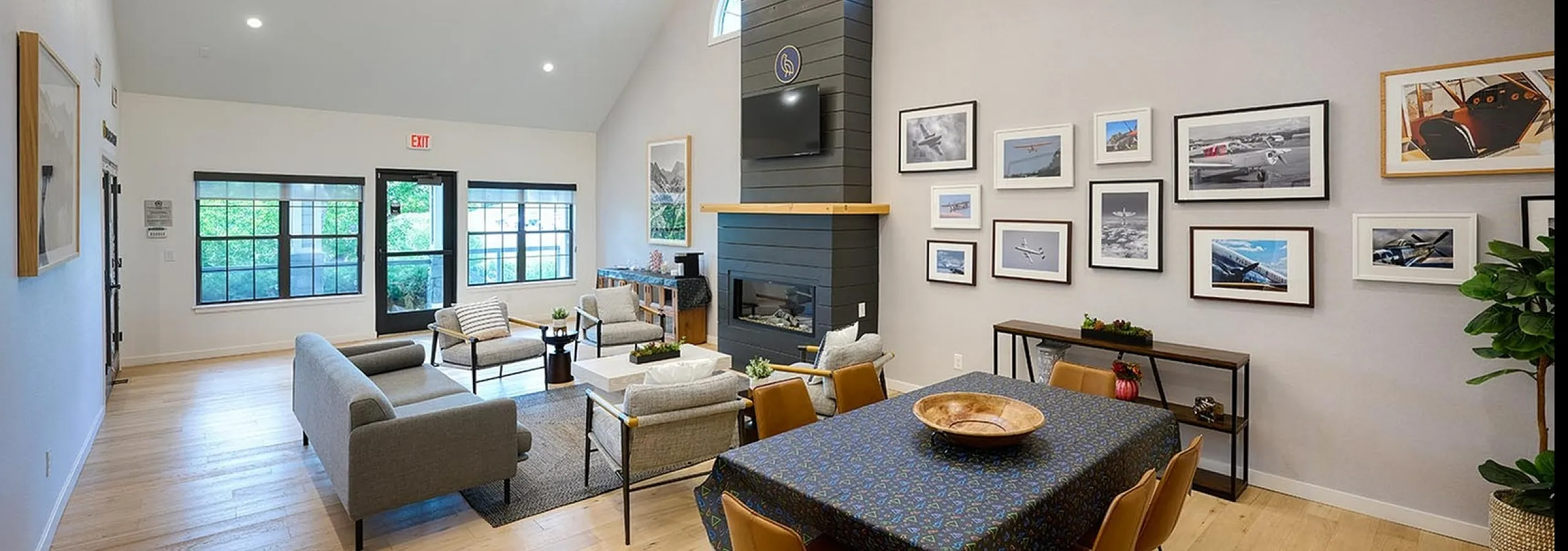 Stylish modern living room with vaulted ceilings, cozy fireplace, elegant chandelier, and vibrant wall art in a spacious open layout.