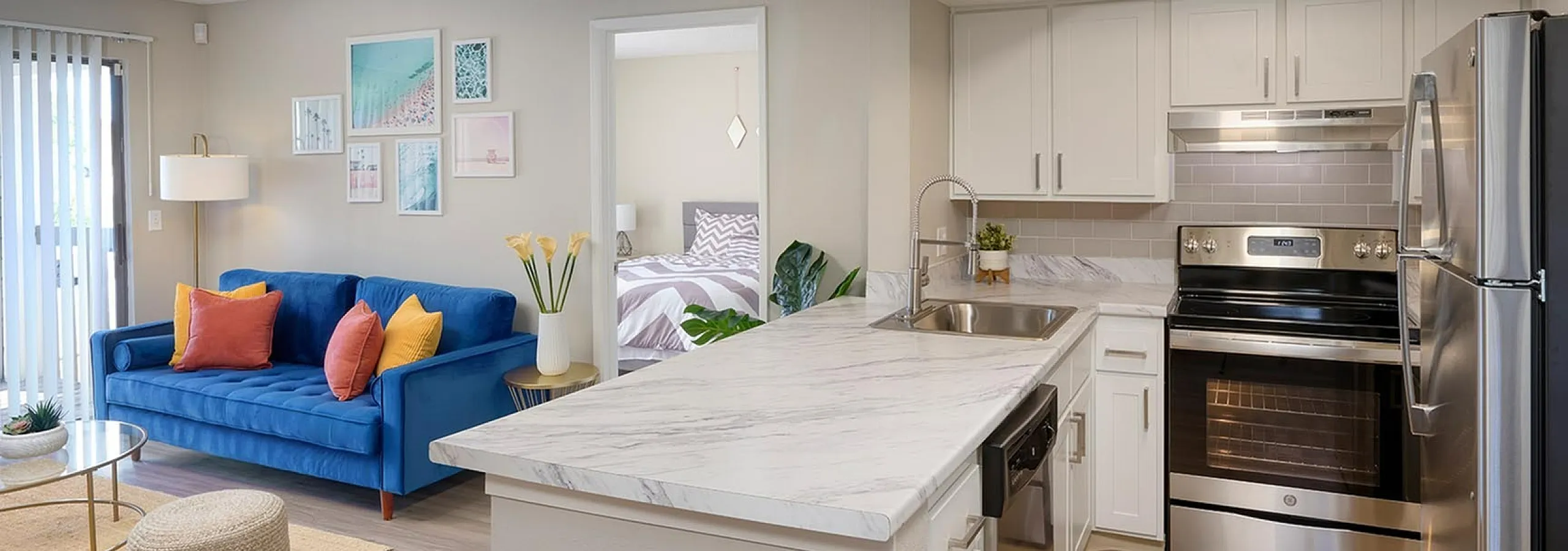 Modern apartment with open-plan living area, vibrant blue sofa, spacious kitchen, and chic decor.