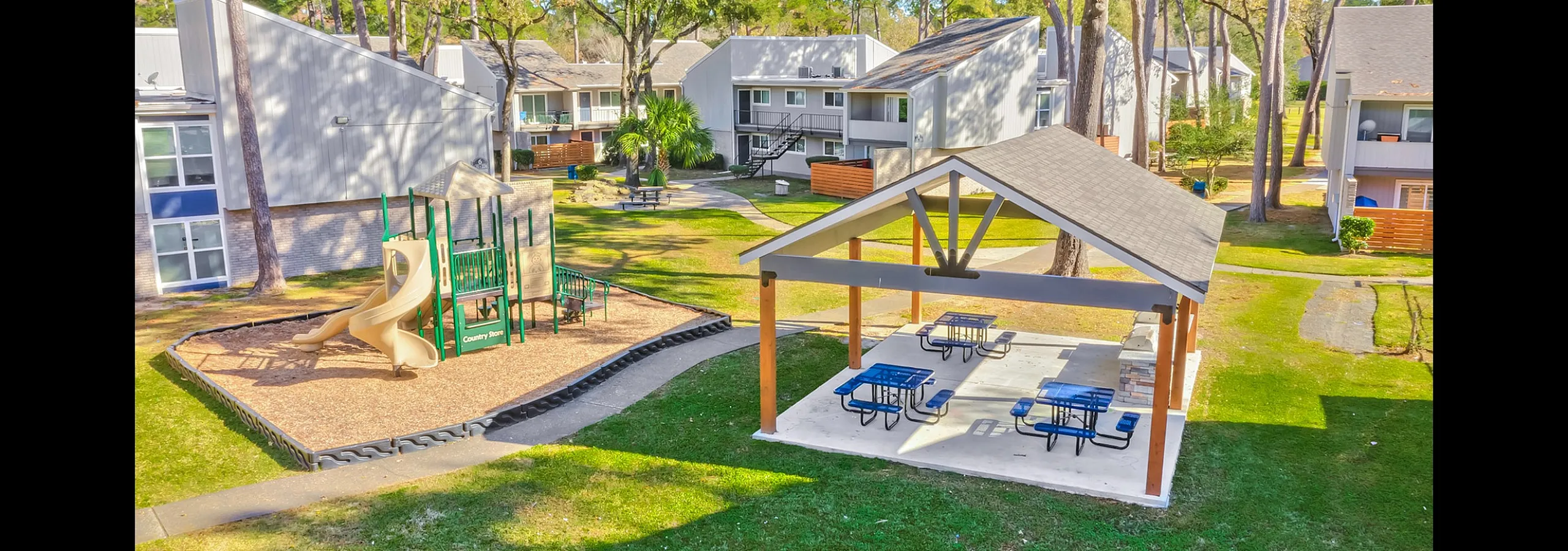 Charming community playground and picnic area surrounded by modern townhouses, with lush greenery and trees creating a peaceful outdoor retreat.