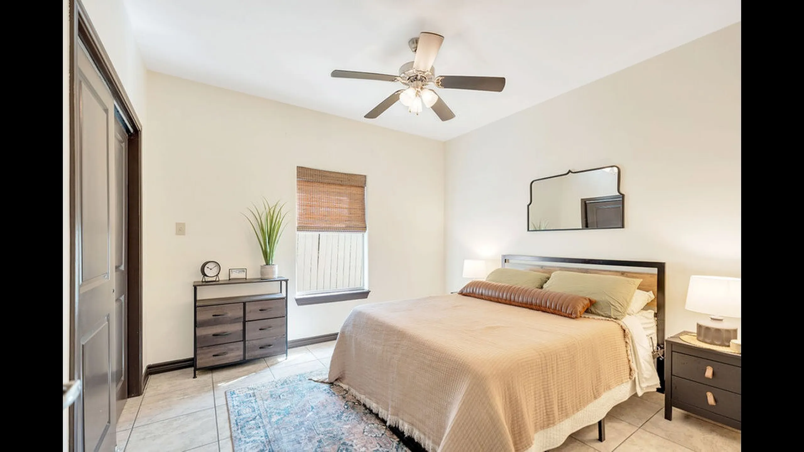 Bright and inviting bedroom with a sleek ceiling fan, cozy bed, elegant nightstands, and warm natural light.