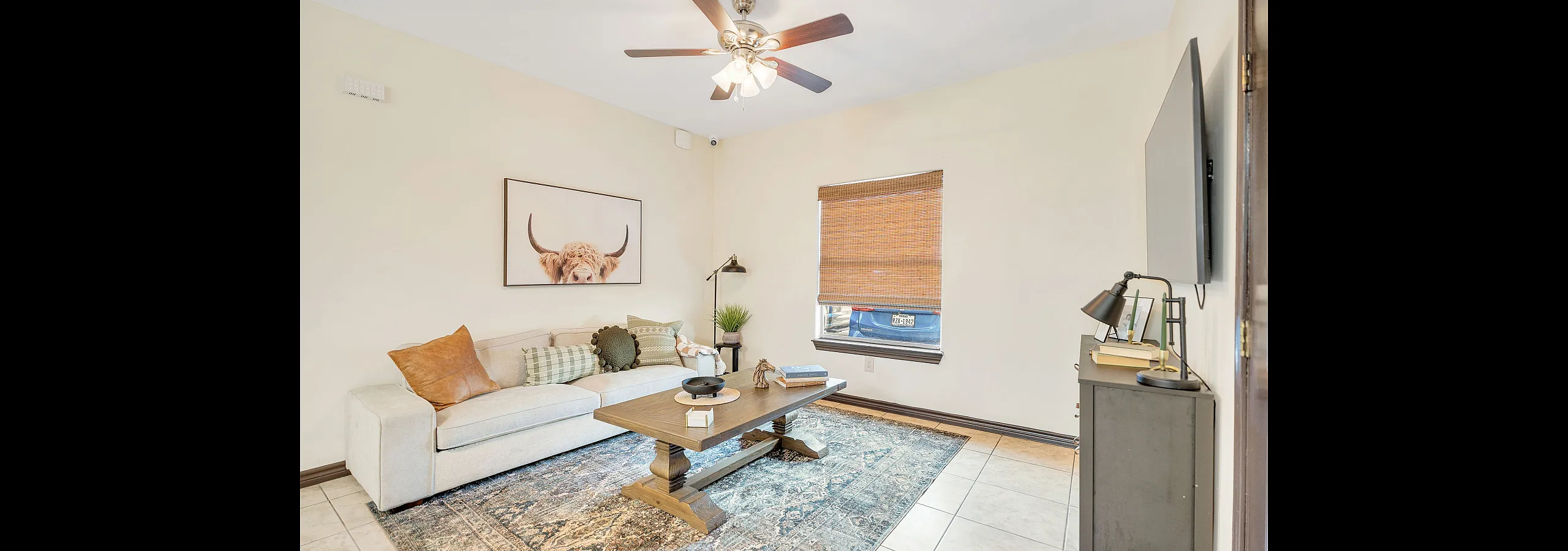 Charming living room with a plush sectional sofa, rustic coffee table, and stylish decor including a large highland cow print on the wall.