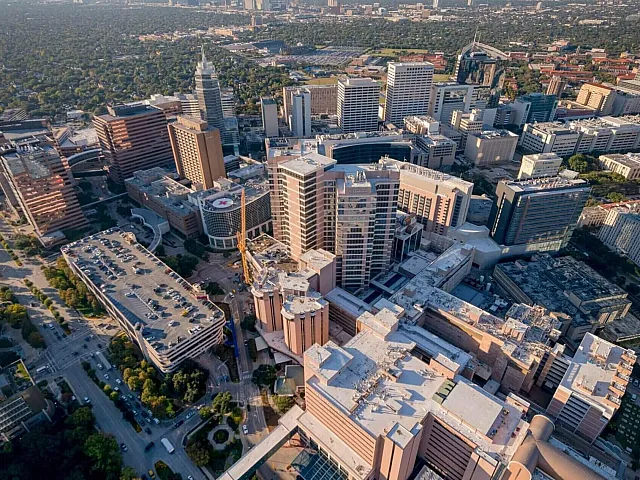 Aerial view of a bustling metropolitan area with modern high-rise buildings, lush green spaces, and a vibrant urban landscape.
