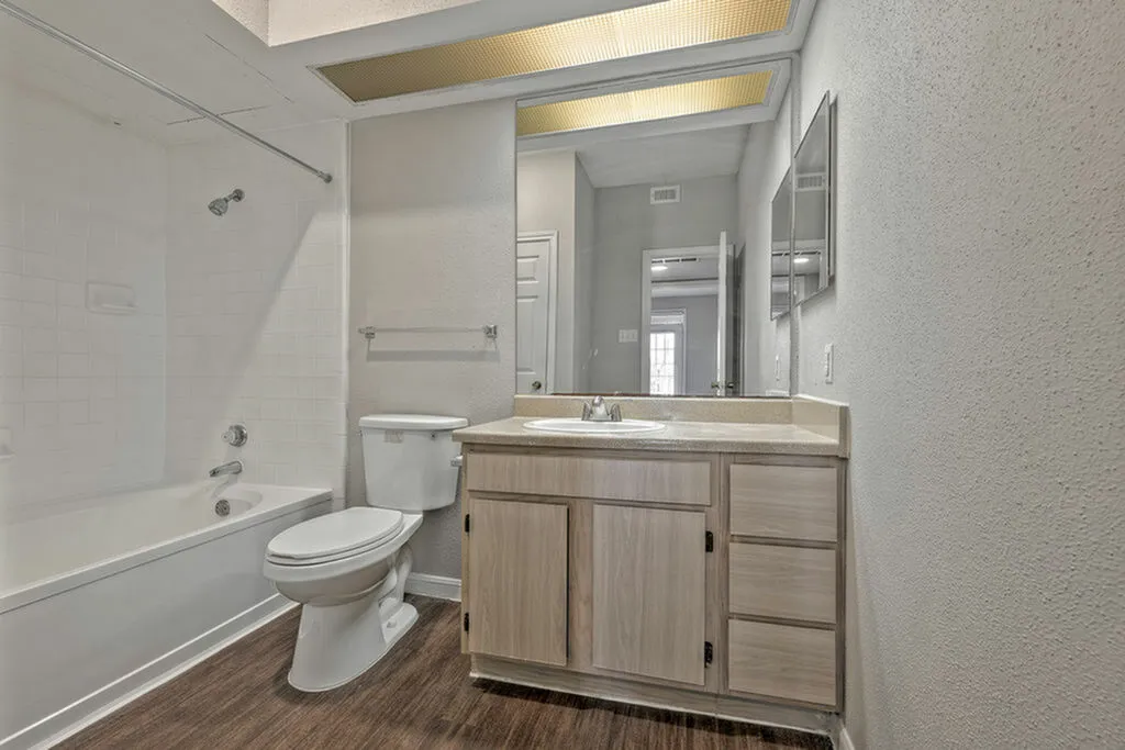 Bright and modern bathroom featuring a spacious vanity, sleek countertop, and pristine bathtub with stylish tile accents.