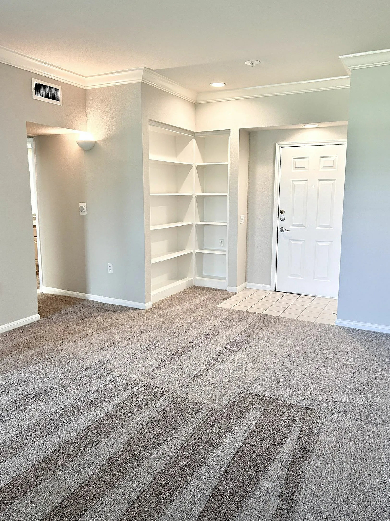 Bright entryway with built-in shelving, cozy carpeted flooring, and modern recessed lighting.