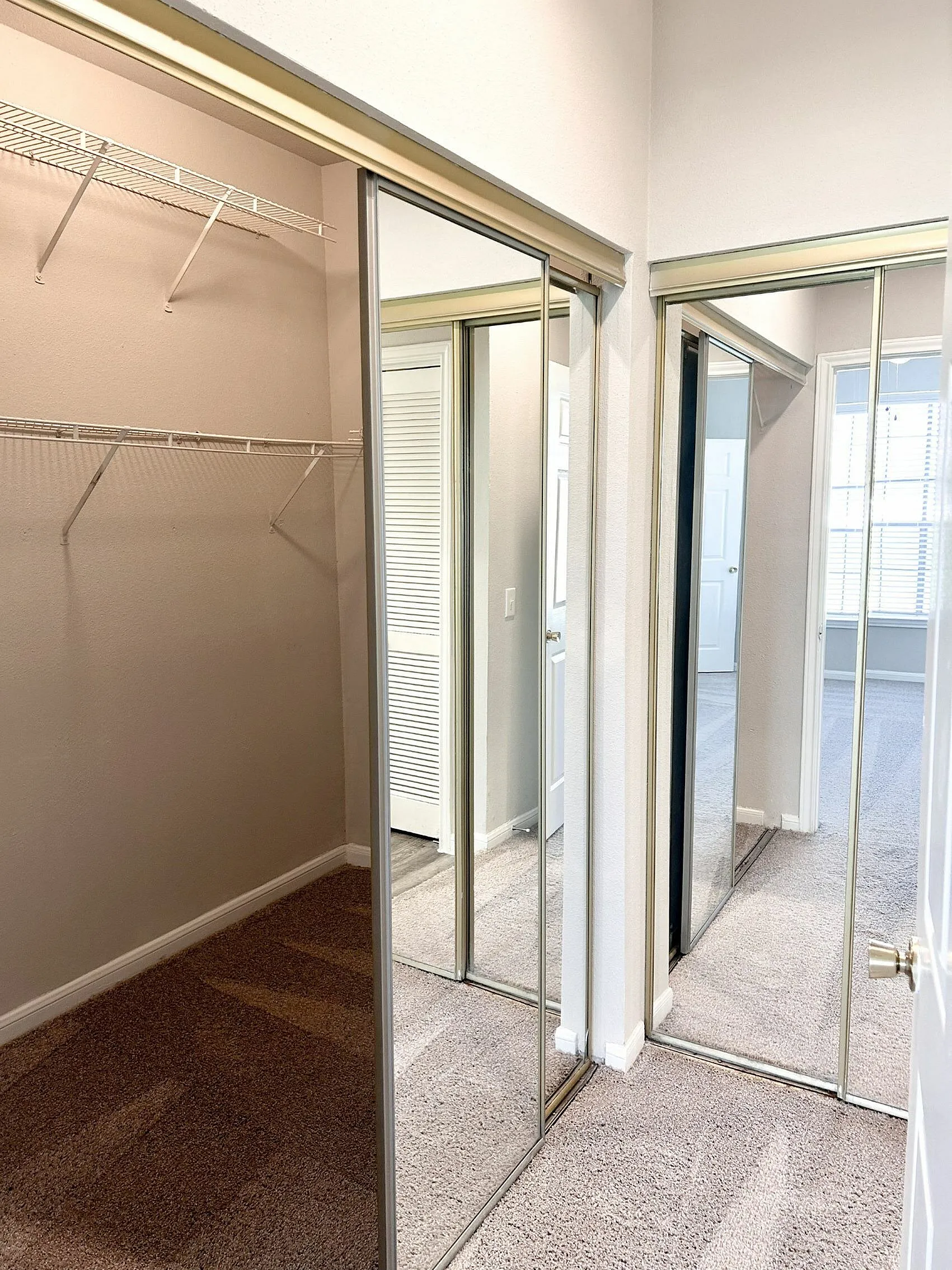Modern walk-in closet with mirrored sliding doors and ample shelving, offering a spacious and bright storage solution.