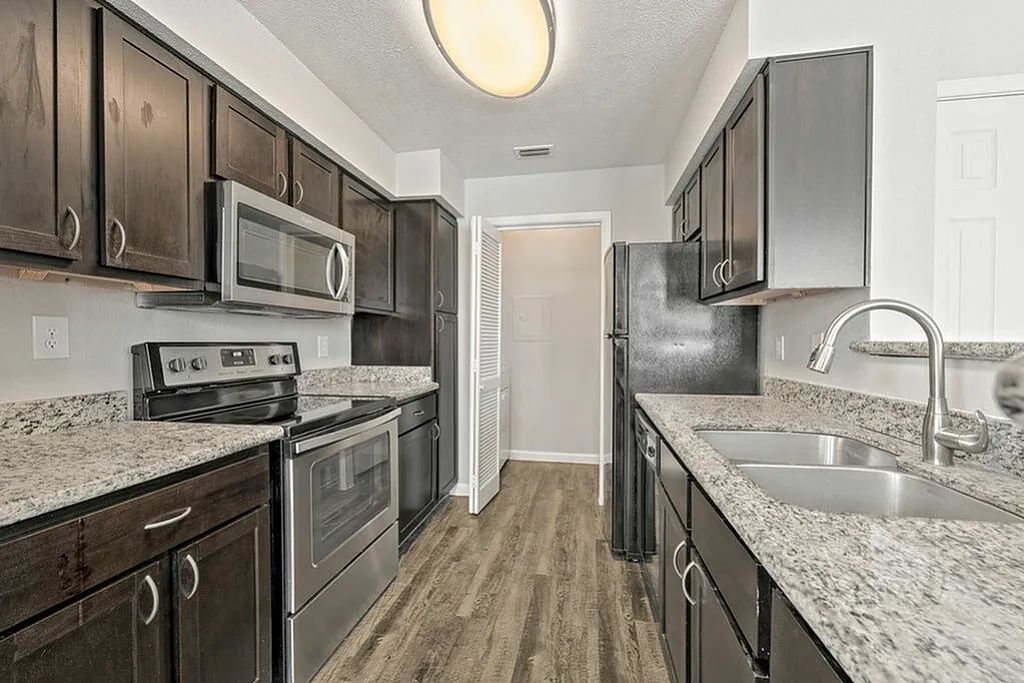 Modern kitchen with sleek dark wood cabinets, stainless steel appliances, and granite countertops.