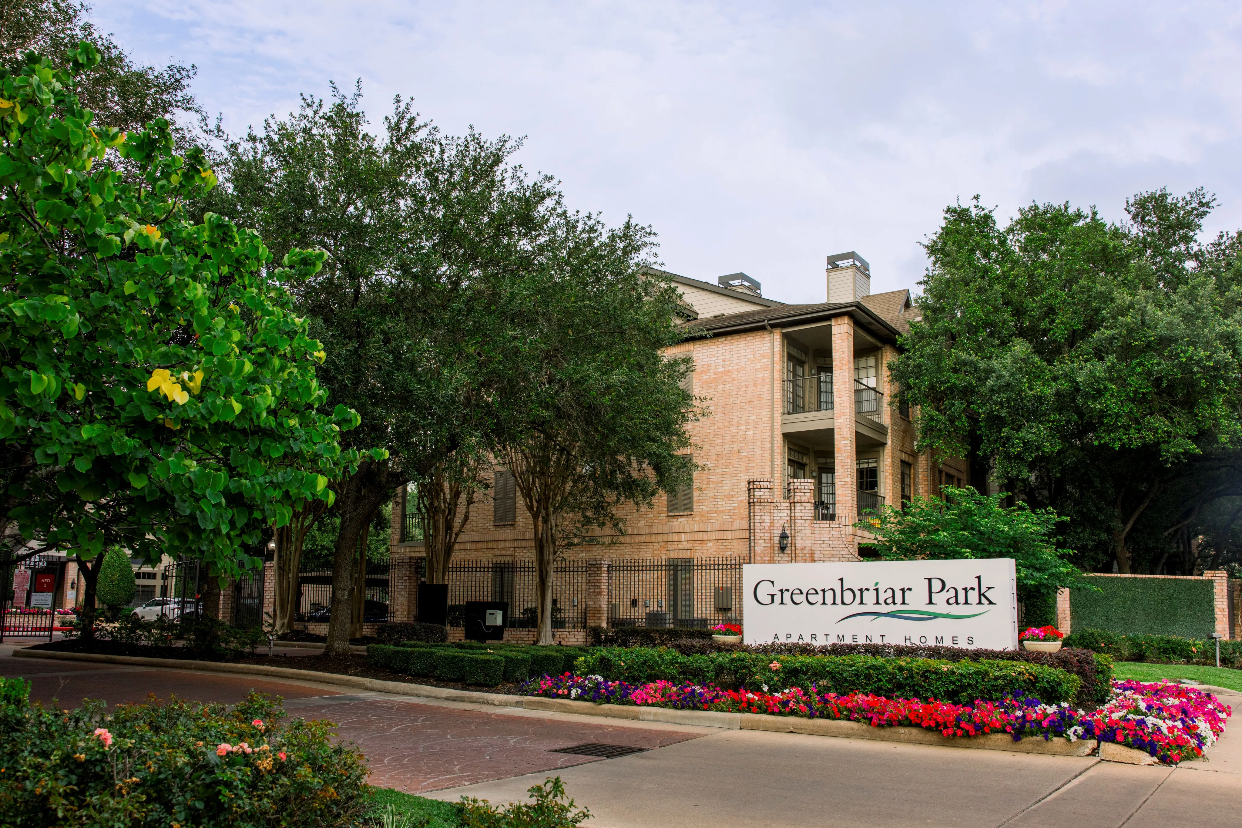 Charming Greenbriar Park apartment complex surrounded by lush greenery and vibrant flowers, offering a serene and welcoming atmosphere.