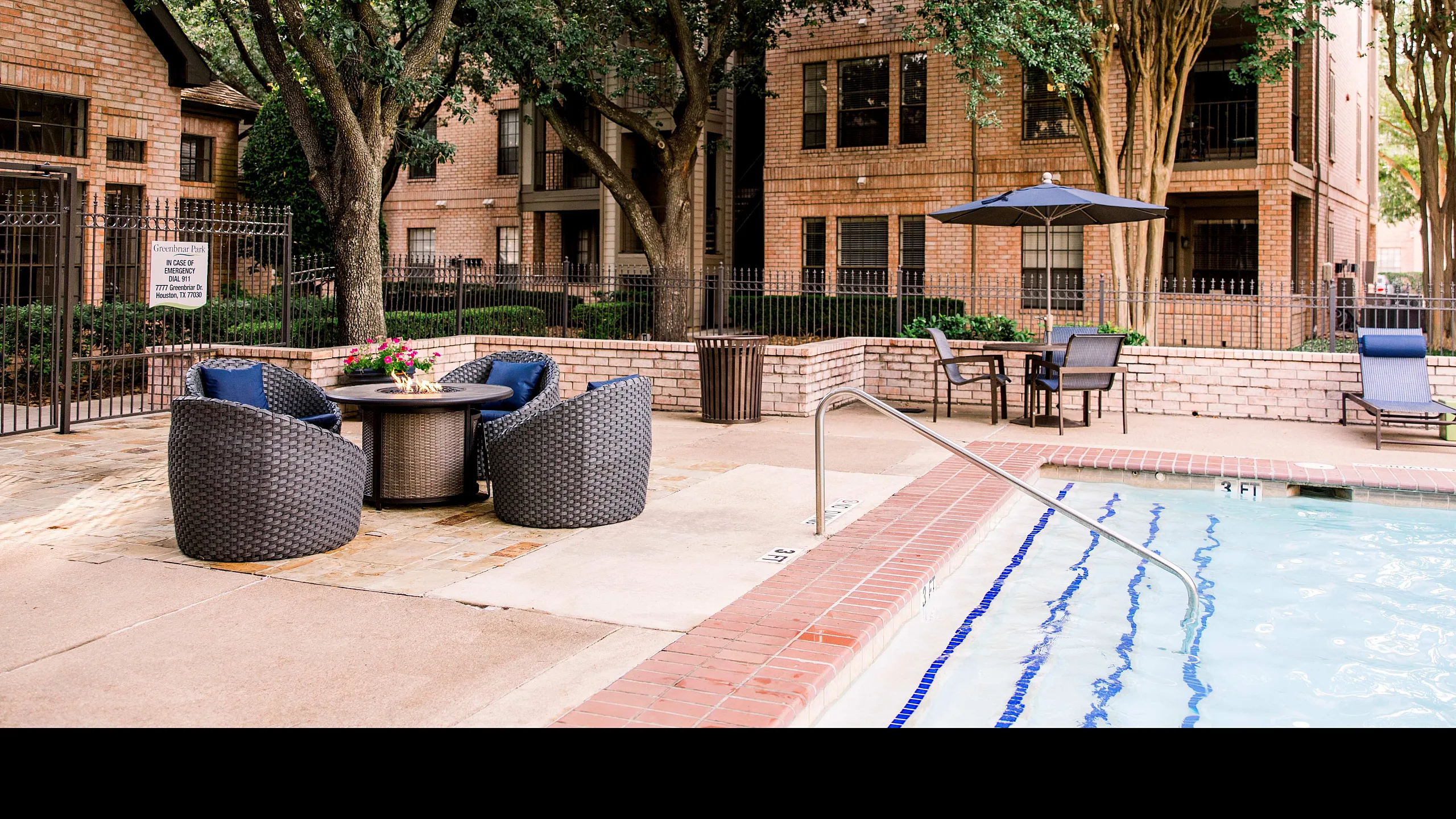 Tranquil apartment courtyard featuring elegant lounge chairs, a stylish poolside patio, and lush greenery creating a serene escape.