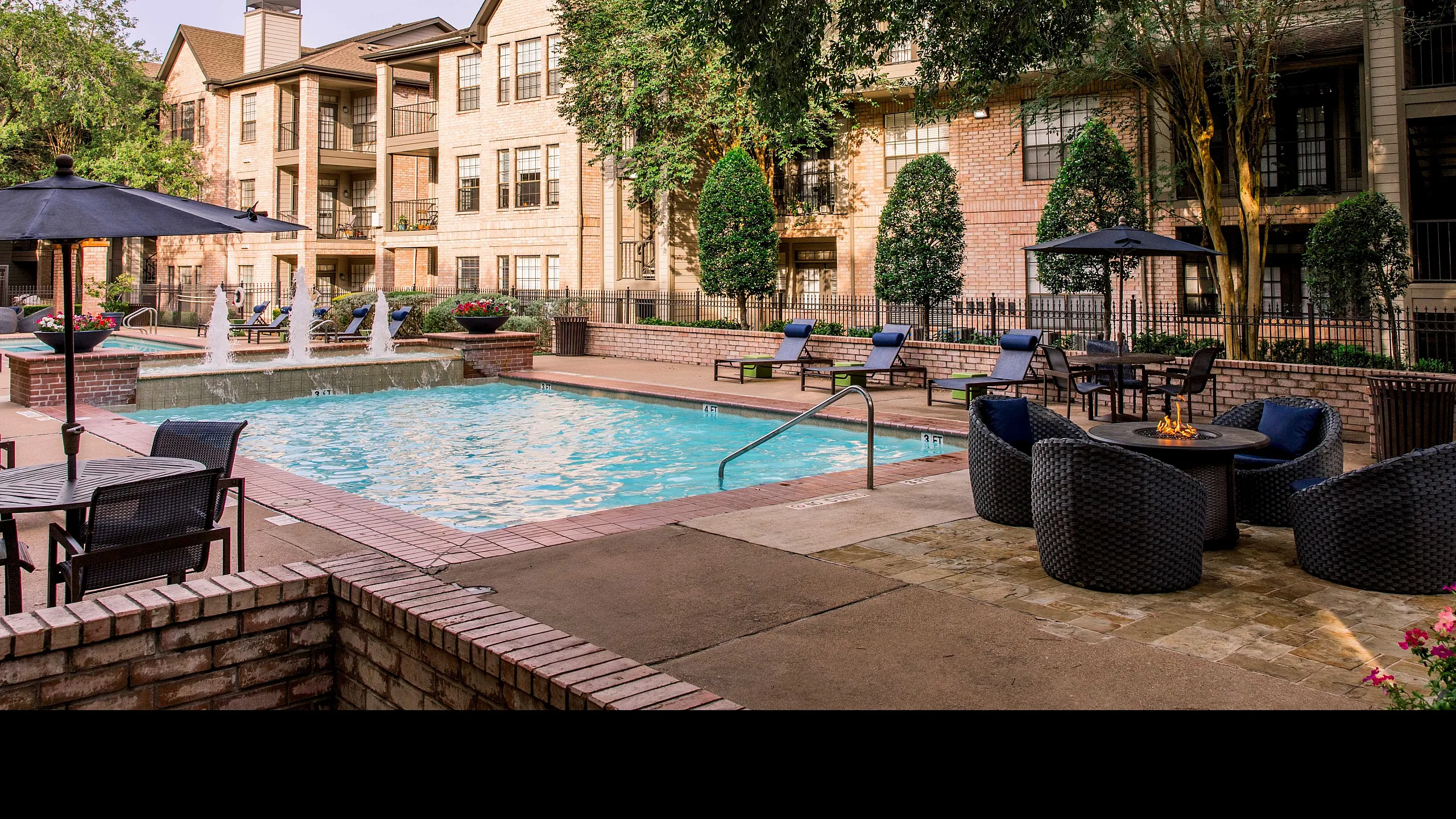 Luxurious apartment complex with sparkling pool, elegant loungers, and lush greenery, perfect for relaxation and leisure.
