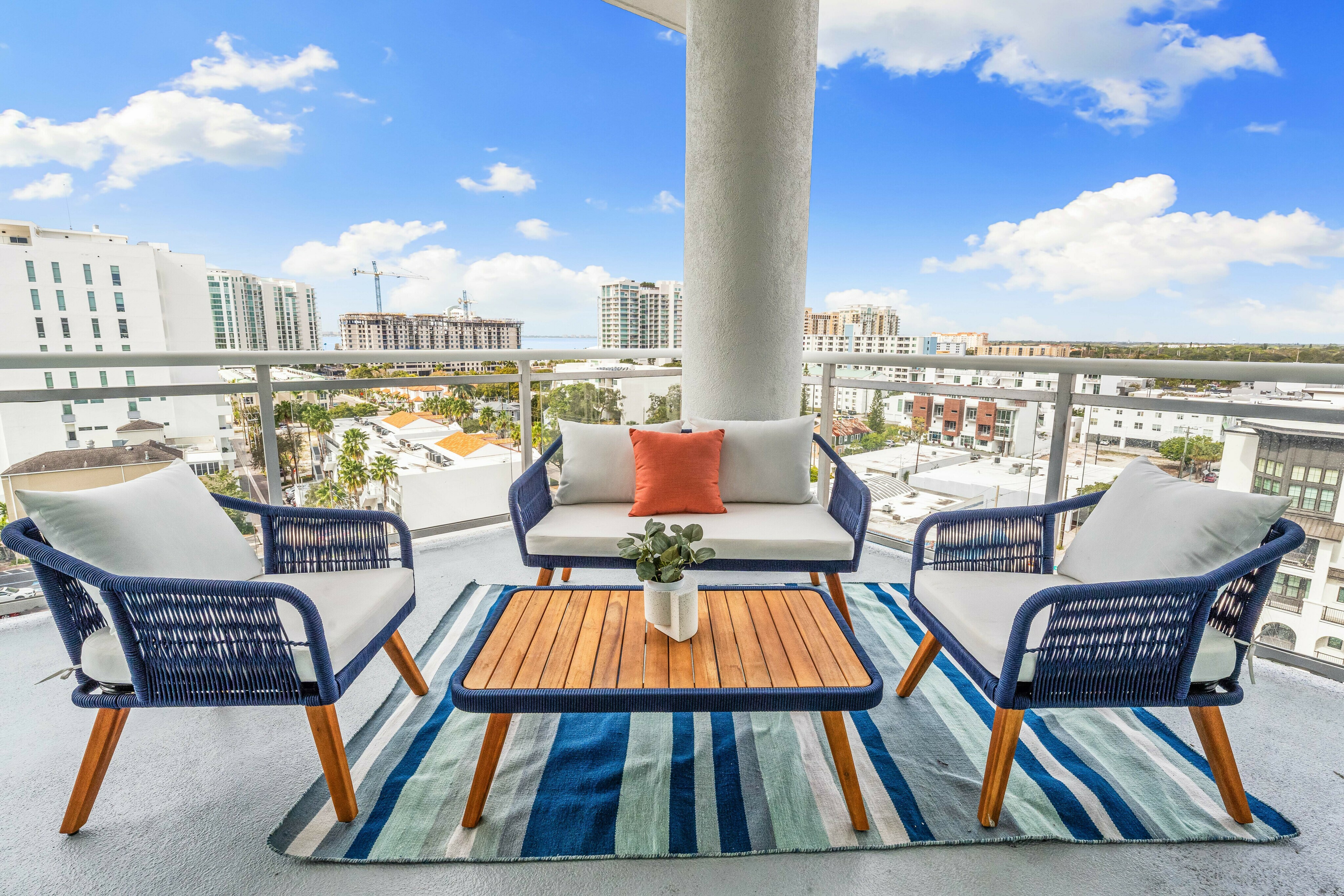 View from balcony in downtown Sarasota featuring a clear blue sky, patio chairs for lounging and a table for hosting. 