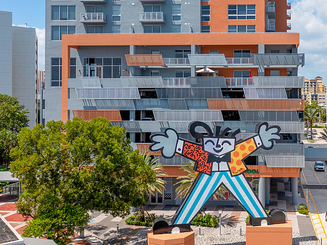 Vibrant urban apartment building with dynamic mural, offering modern living spaces and balcony views.
