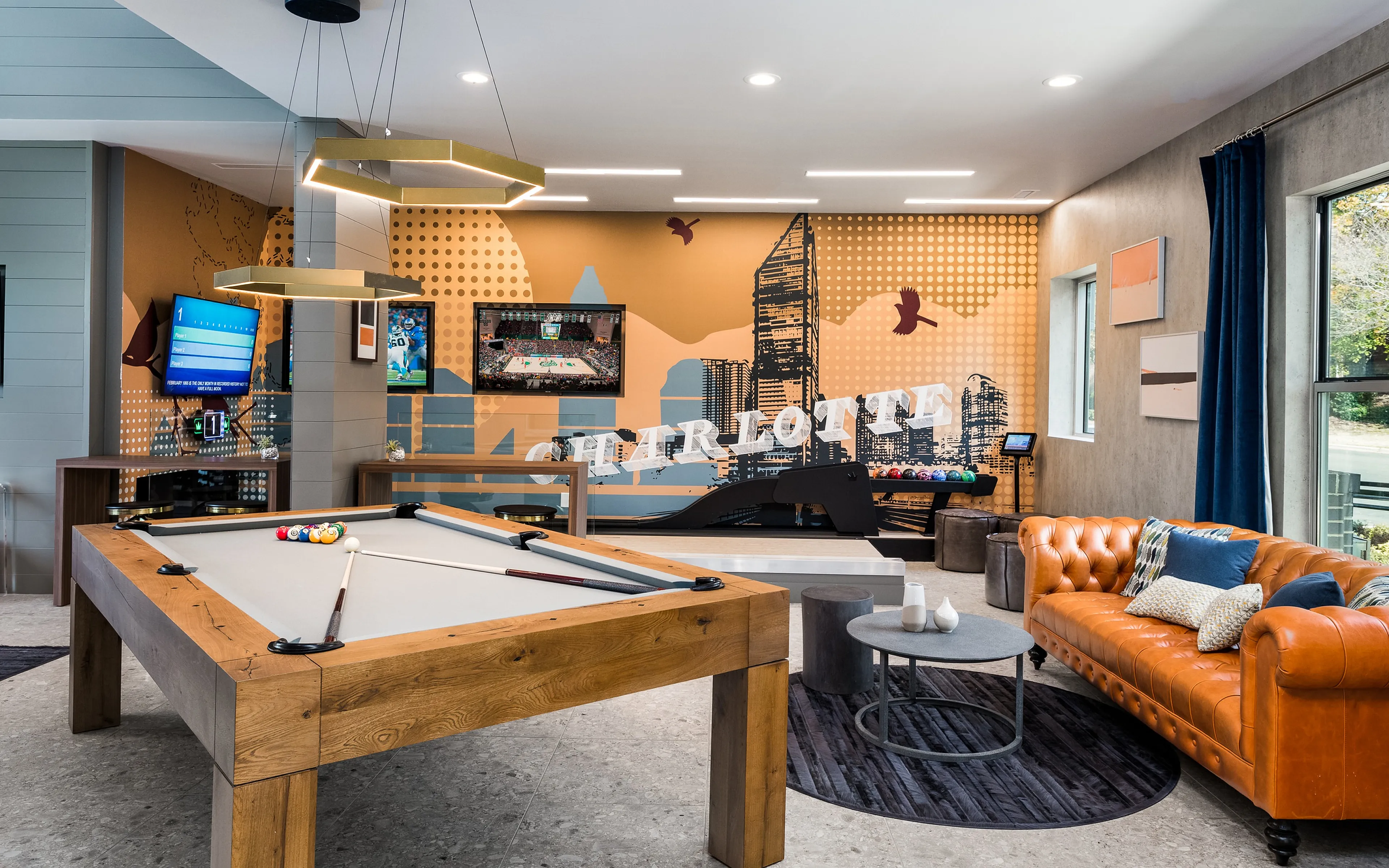 Modern apartment game room with a pool table, leather sofa, and vibrant wall art