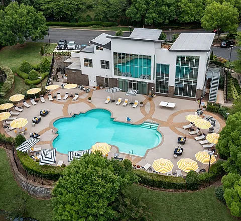Aerial view of a luxurious apartment's pool area with modern architecture and vibrant umbrella seating.