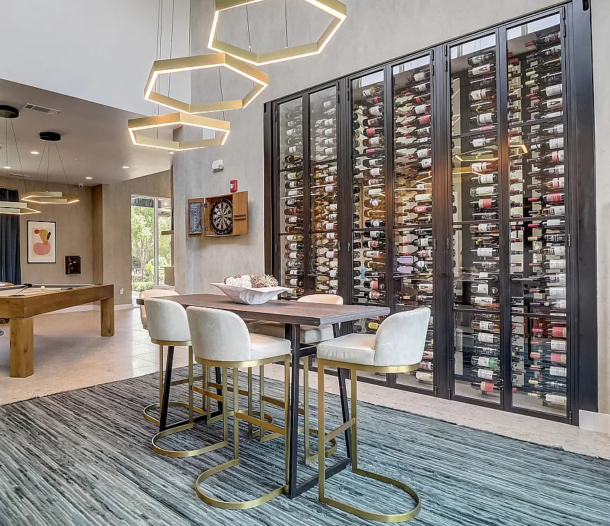 Luxurious apartment lounge with wine wall, modern lighting, and pool table.