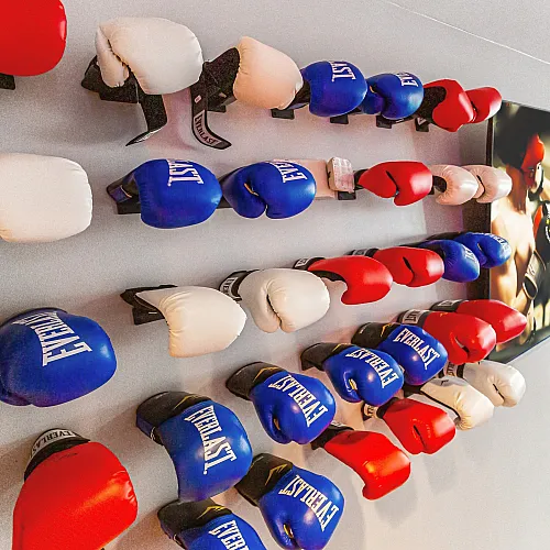 Colorful array of boxing gloves mounted on a gym wall with vibrant lighting.