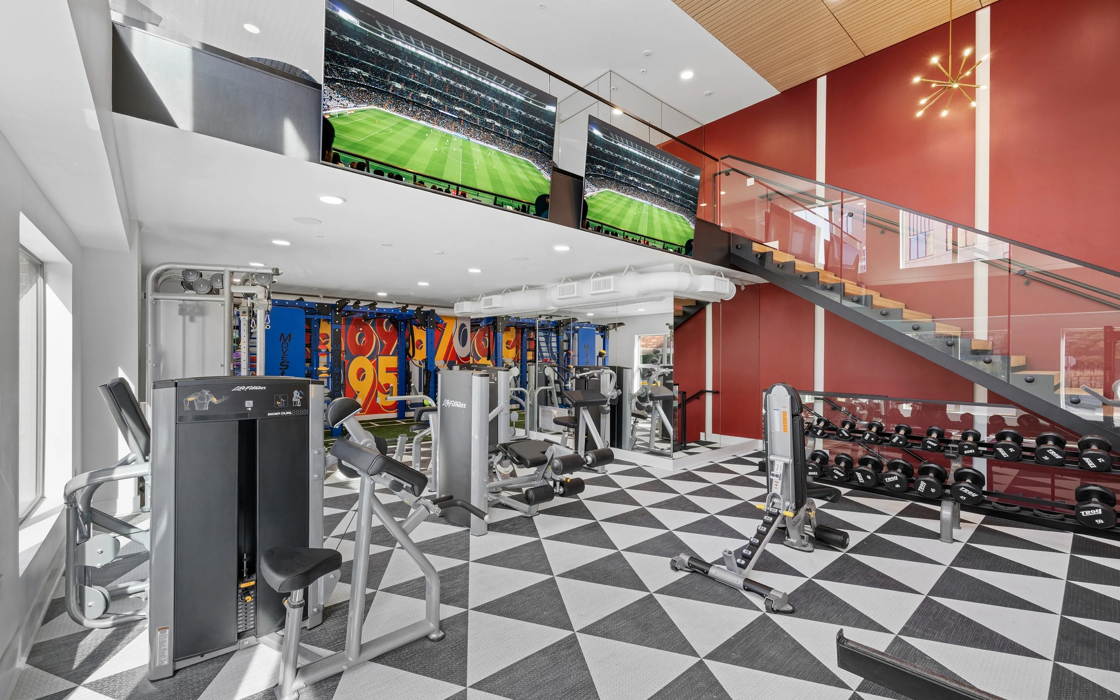 Modern gym with state-of-the-art equipment and large TVs in a luxurious apartment building.