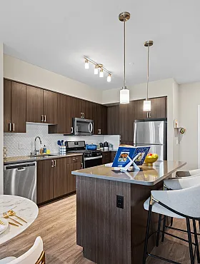 high end apartment kitchen with brown cabinets and stainless steel appliances