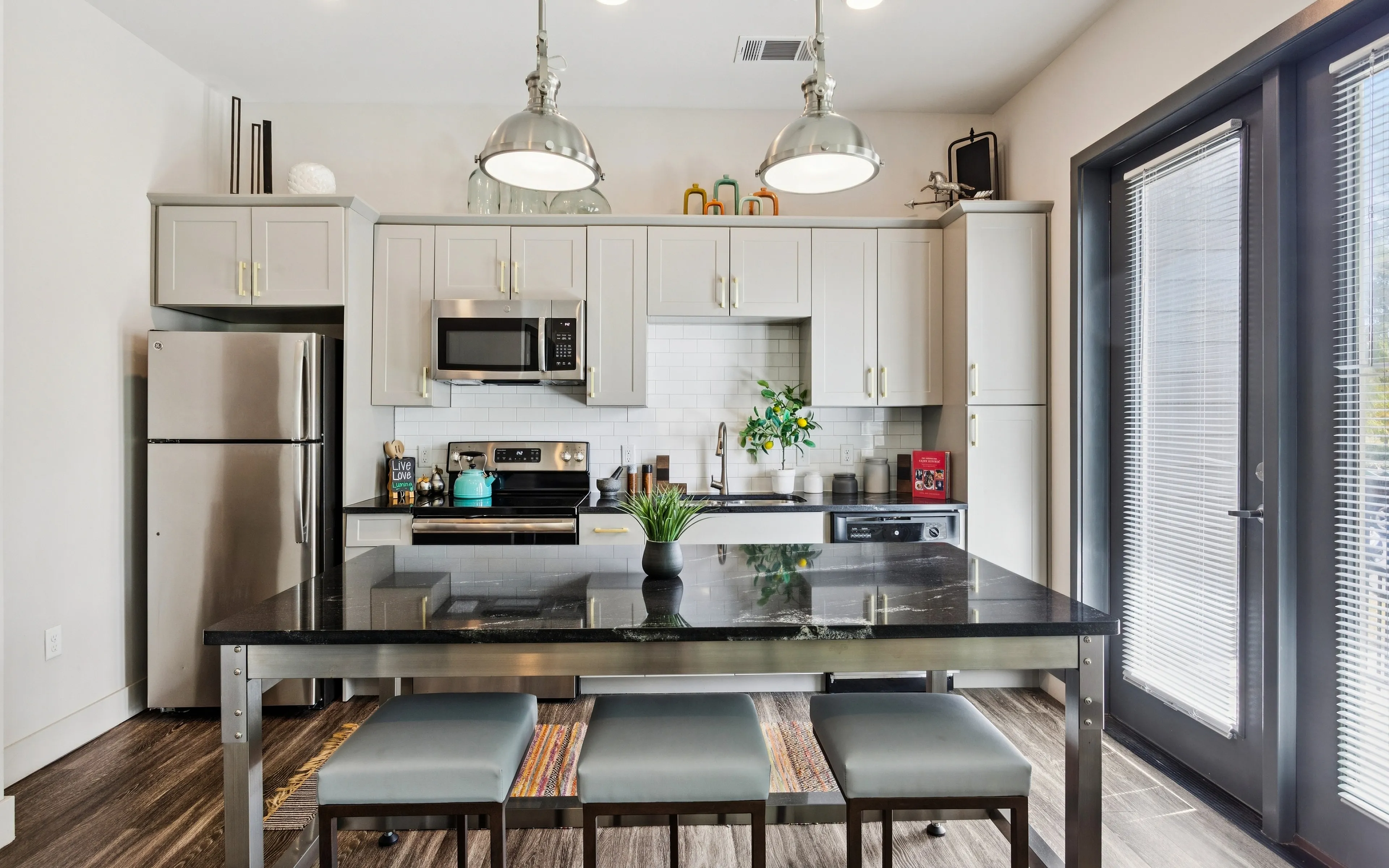Modern kitchen with sleek stainless steel appliances, elegant pendant lights, and a stylish black countertop with comfortable seating.