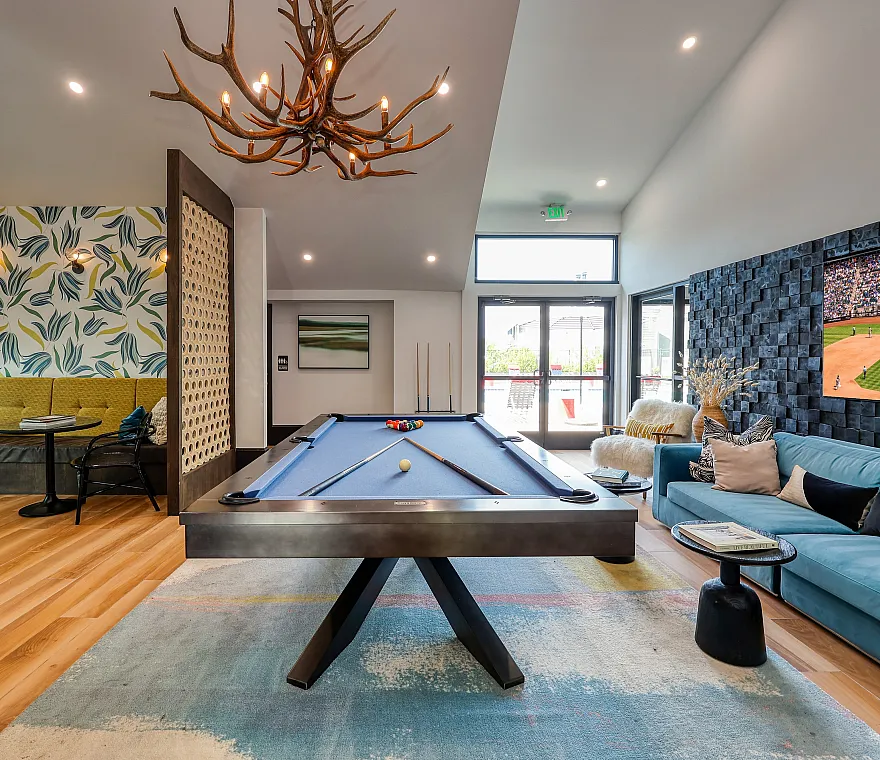 Luxurious entertainment lounge with modern pool table, plush seating, vibrant artwork, and large TV, perfect for social gatherings.