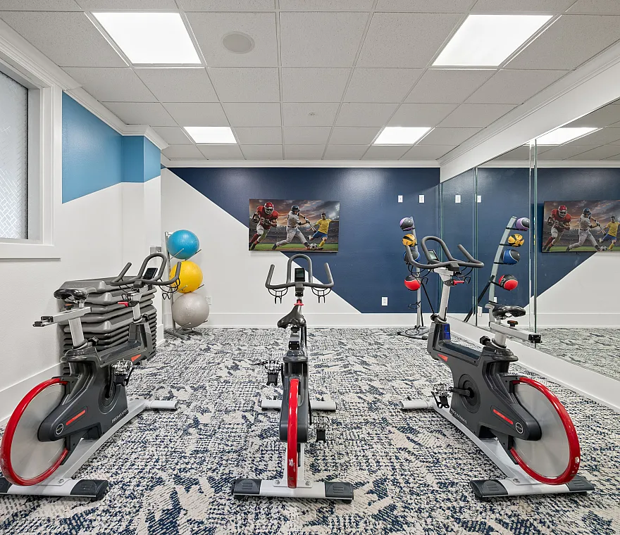 Modern fitness room with high-end exercise bikes, vibrant blue and white decor, and inspirational sports artwork.
