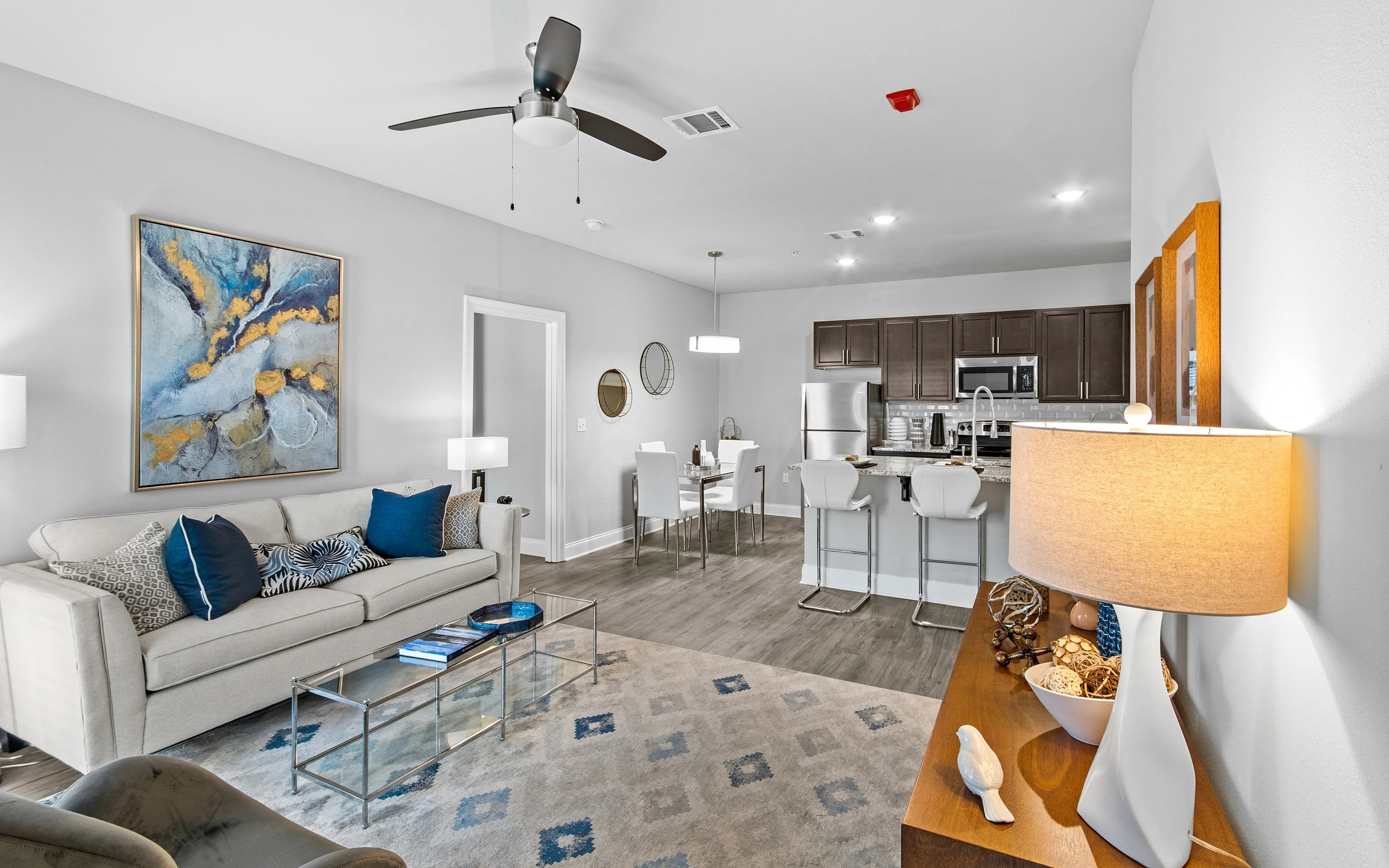Modern open-concept living space featuring a sleek kitchen with dark cabinetry, elegant dining area, and cozy living room with stylish decor.