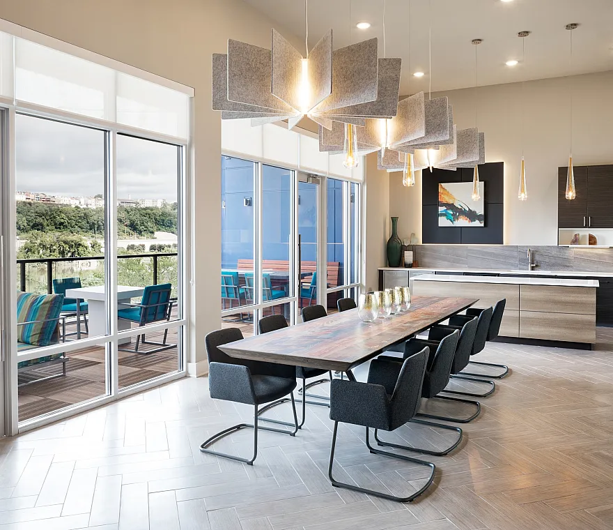 Modern open-concept dining area with elegant lighting, a sleek kitchen, and floor-to-ceiling windows leading to a scenic balcony view.