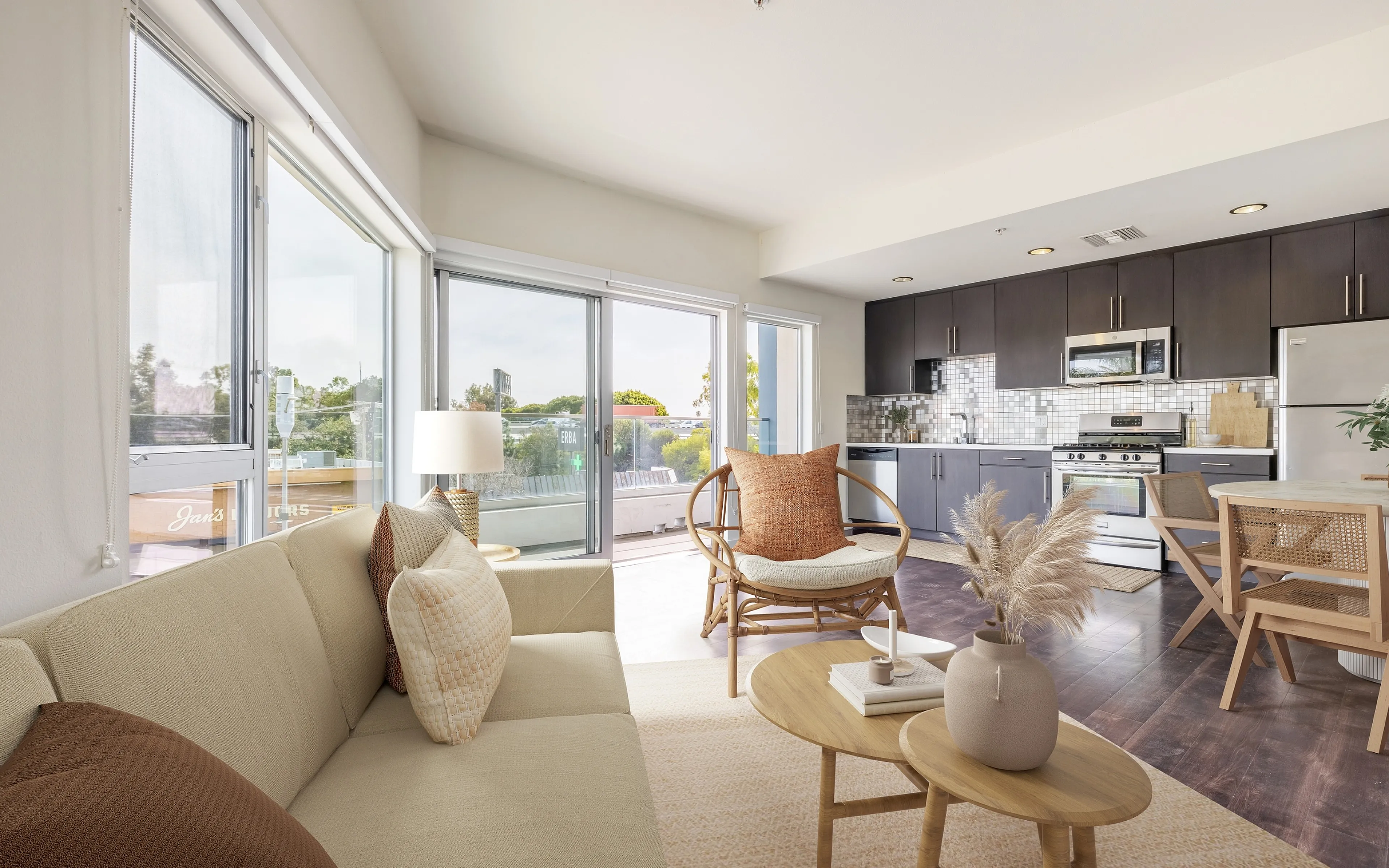 Bright and modern open-concept living space with sleek kitchen, comfortable seating, and abundant natural light from large windows.