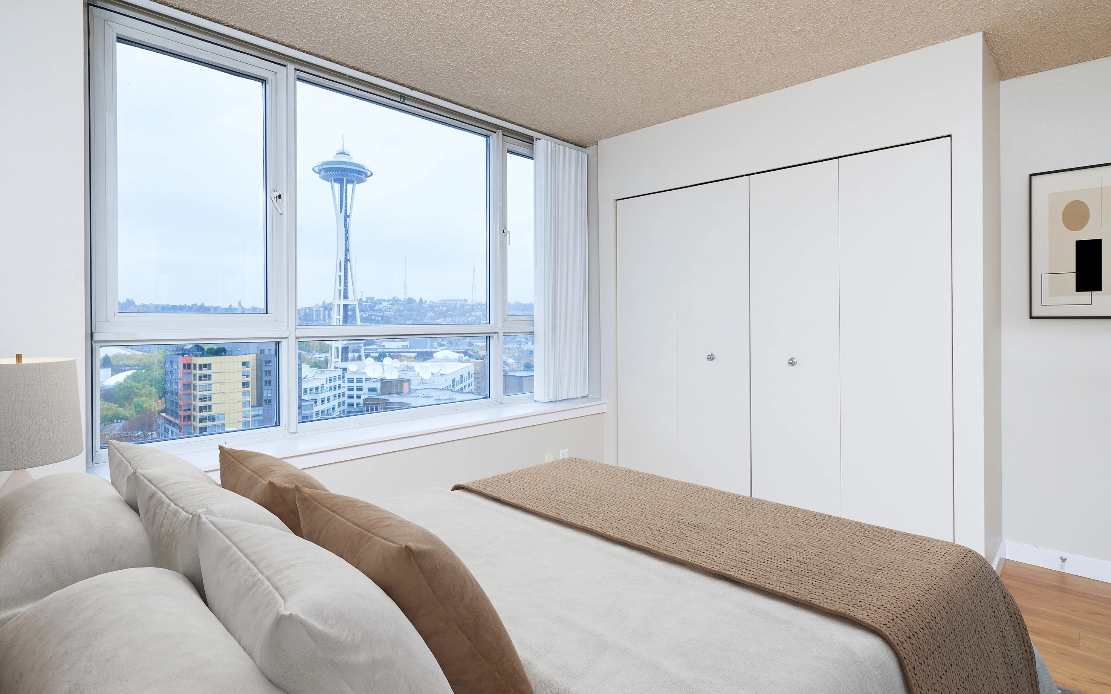 Modern bedroom with a stunning view of the Space Needle, featuring large windows, cozy bedding, and contemporary decor.