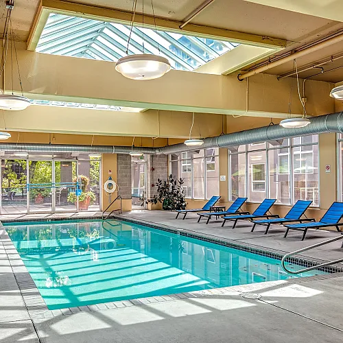 Modern indoor pool area with skylights and relaxing lounge chairs, offering a luxurious retreat.