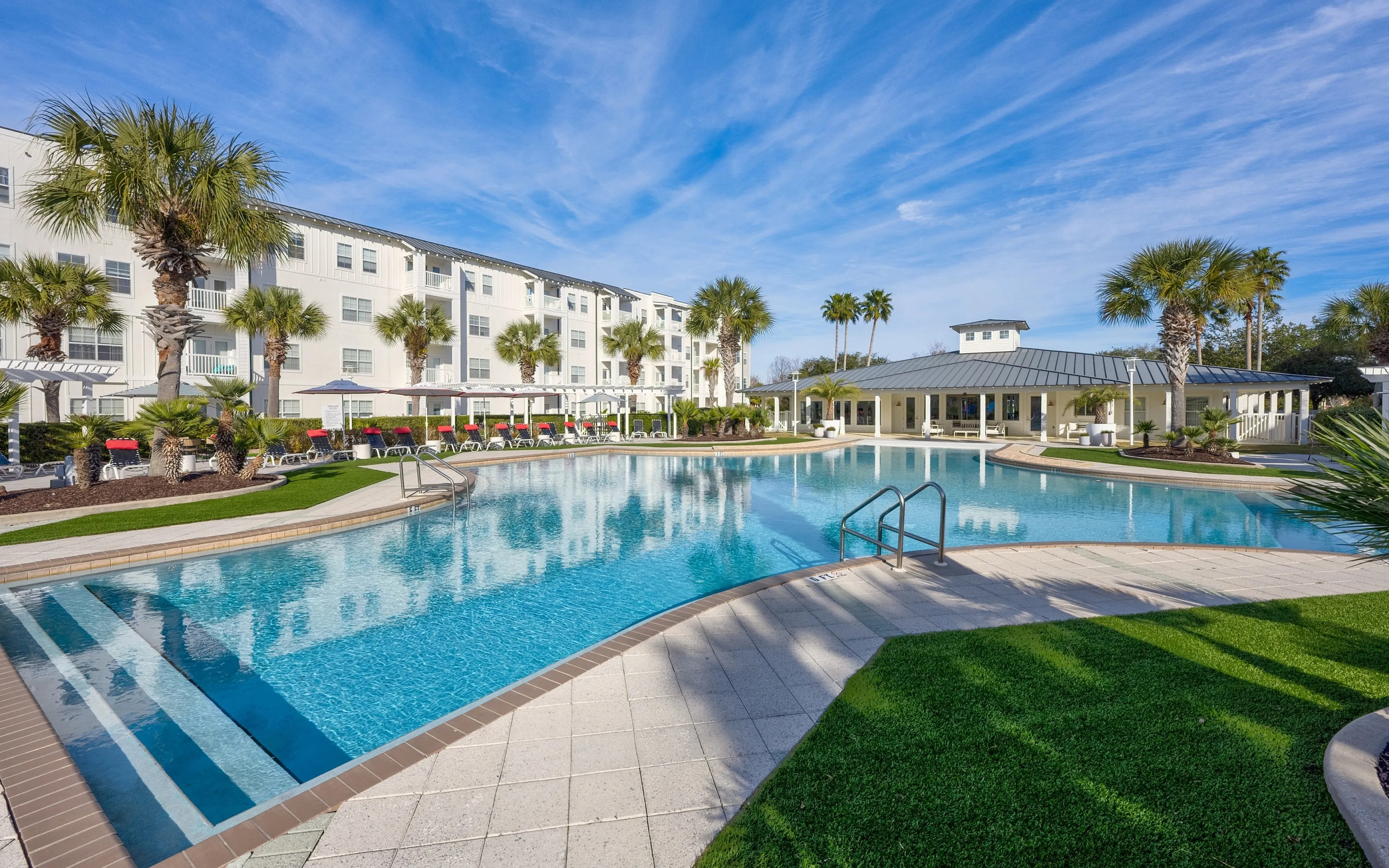 Luxurious apartment complex featuring a stunning poolside oasis surrounded by lush palm trees and modern amenities, perfect for relaxation and leisure.