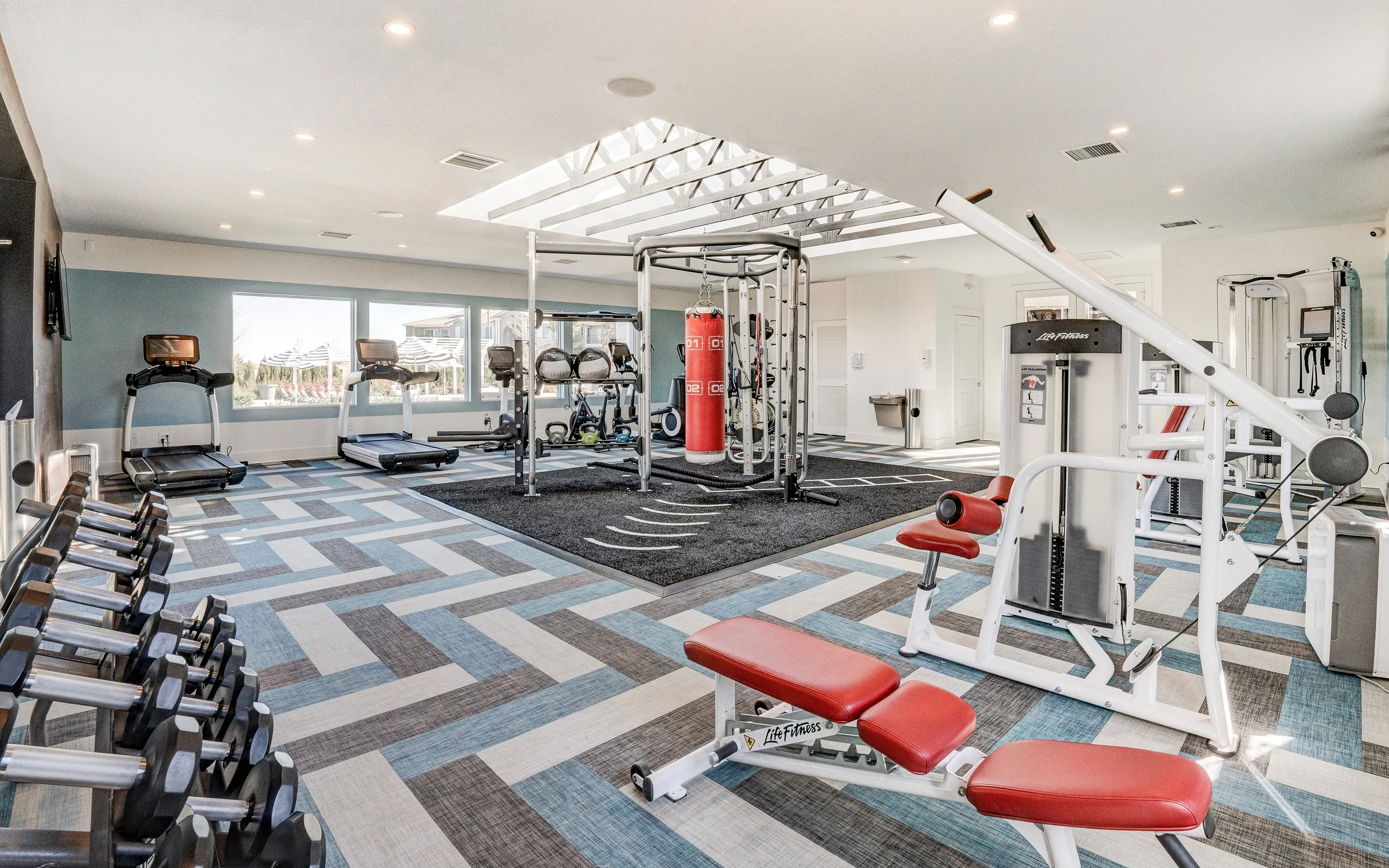 Bright, modern fitness center featuring top-of-the-line equipment, skylights, and a stylish design.
