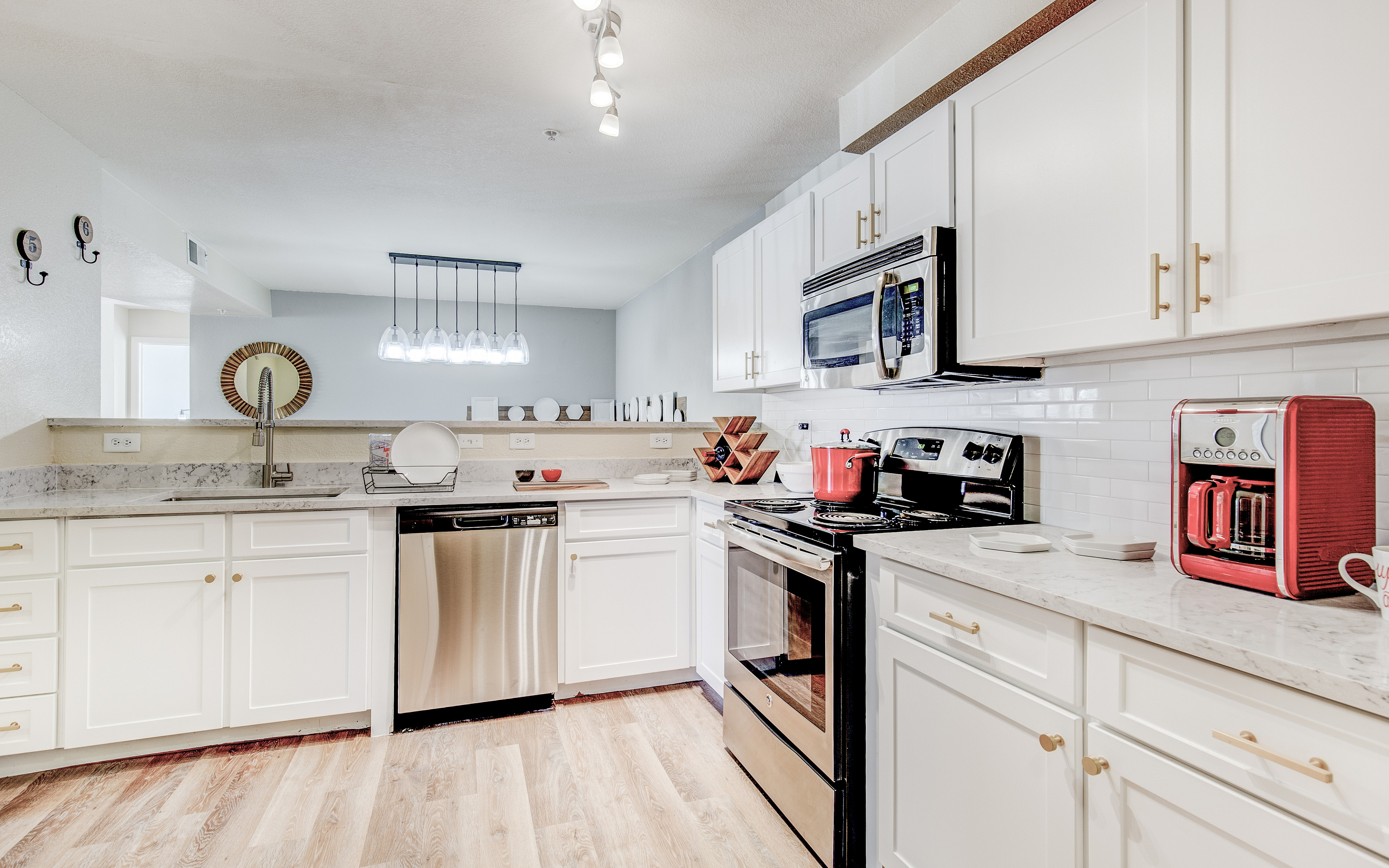 Modern kitchen with elegant white cabinetry, stainless steel appliances, and stylish lighting, perfect for culinary enthusiasts.