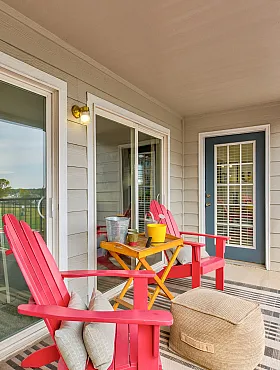 Charming apartment balcony featuring cozy red chairs, a stylish rug, and scenic views, perfect for relaxing and entertaining.