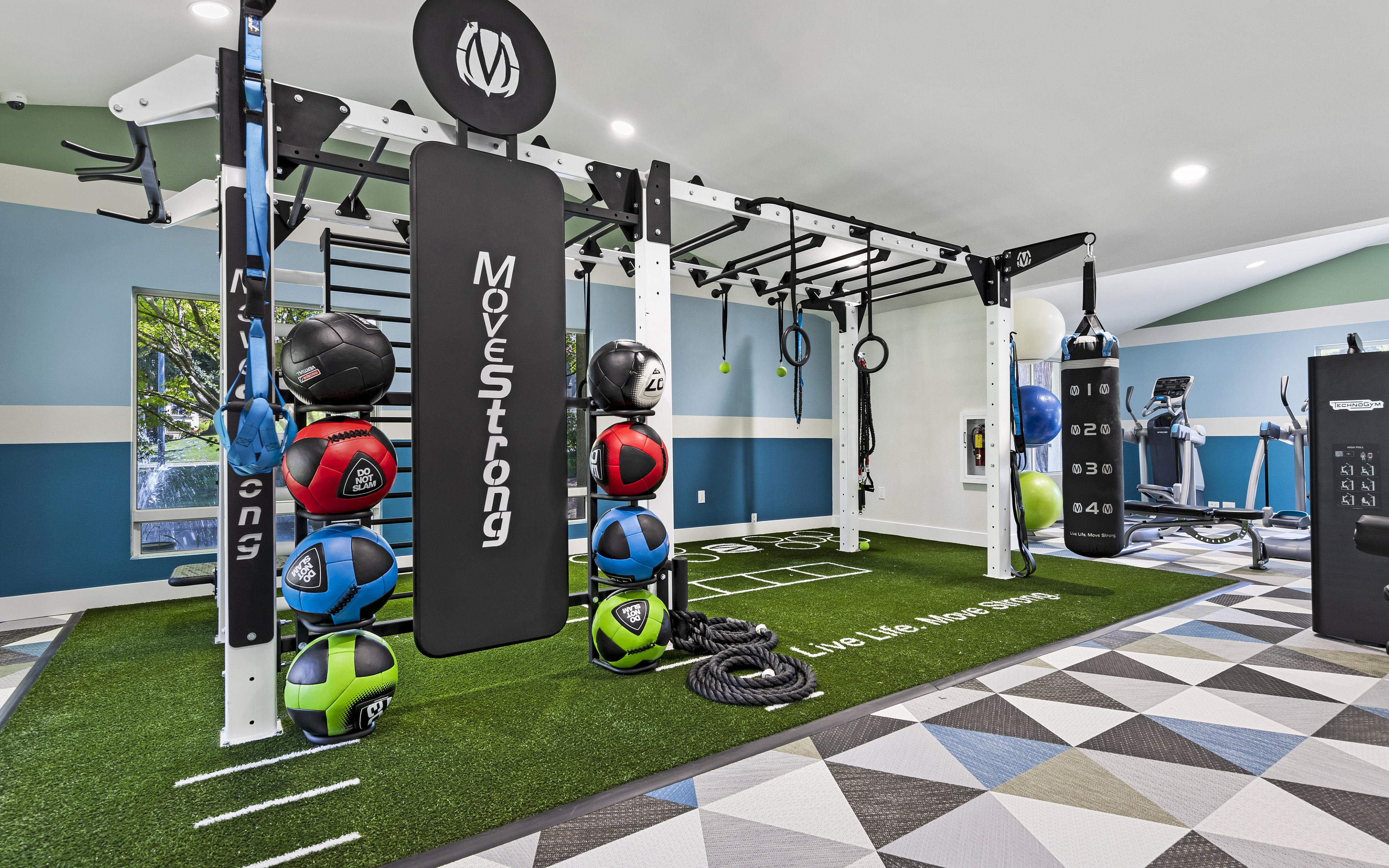Modern fitness center with advanced MoveStrong equipment, featuring colorful medicine balls, climbing ropes, and a boxing bag, creating an inspiring workout environment.