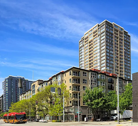 Vibrant cityscape with a modern high-rise apartment building under a clear blue sky, offering urban living with a stunning view.
