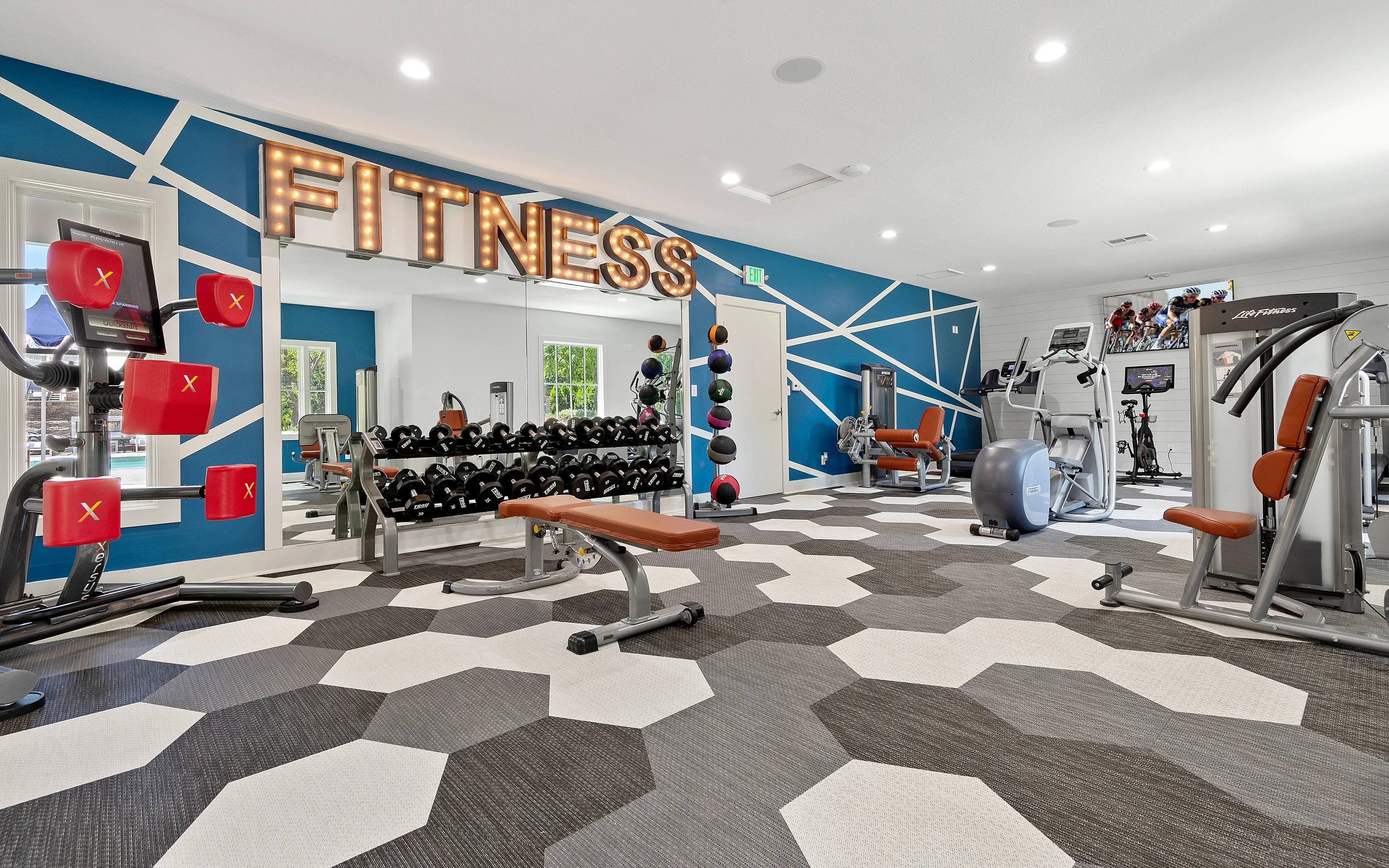 Modern fitness center with vibrant decor, featuring advanced workout equipment and eye-catching geometric flooring.